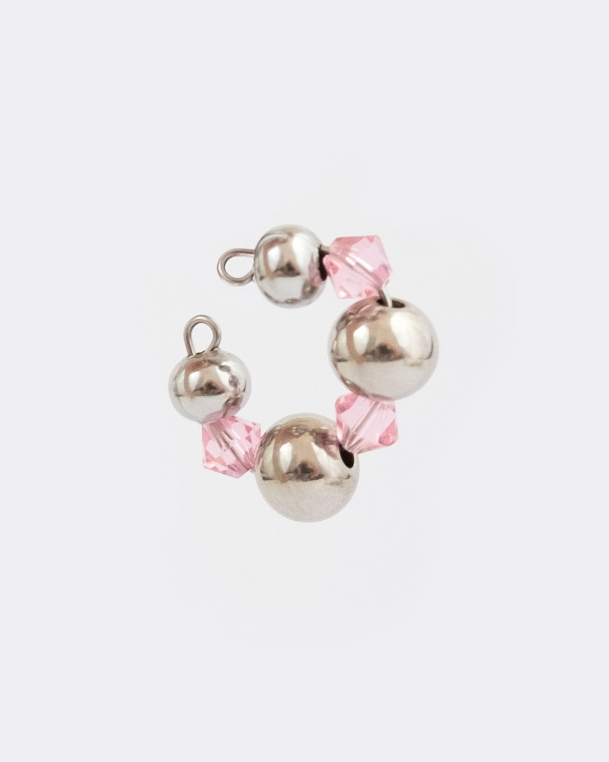 Earcuff en acier inoxydable. Il s’agit d’un faux piercing pour oreille non perçée qui se positionne au niveau du conch ou du lobe suivant la largeur de l’oreille. Il est composé d’un anneau argenté, de perles argentées et en cristal de couleur rose