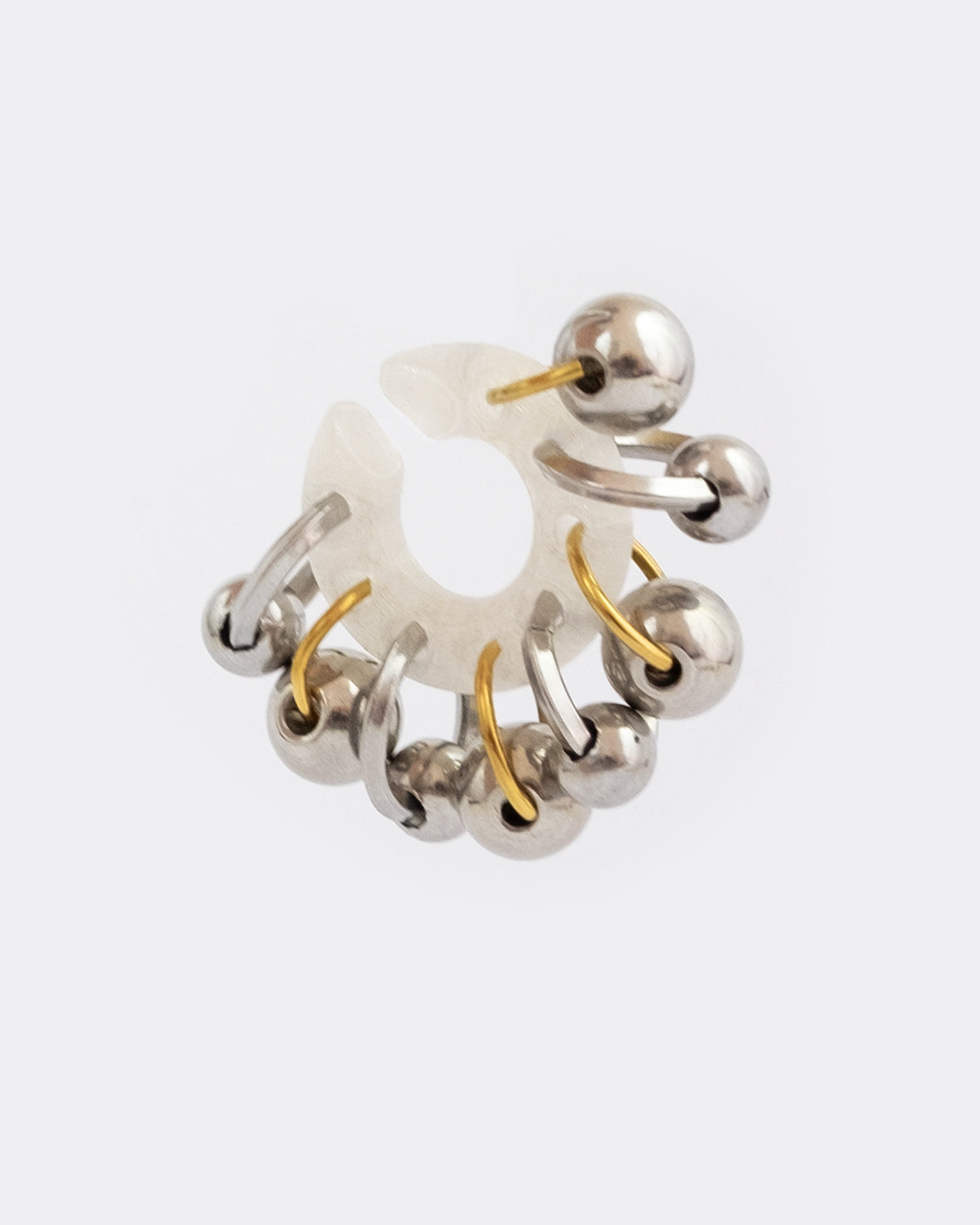 Earcuff en plastique biosourcé. Il est composé d’une multitude d'anneaux et de perles dorés et argentés en quinconce sur une base transparente