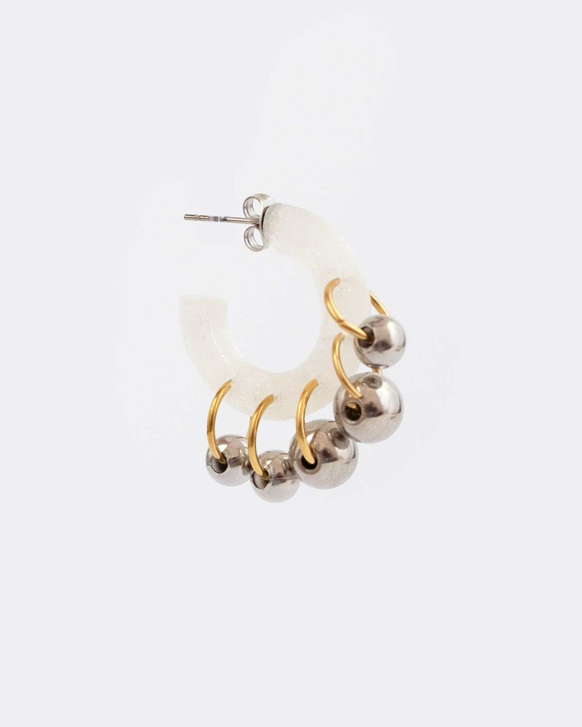 Mono boucle d’oreilles en plastique biosourcé. Elle est composée de différents anneaux et perles dorés et argentés sur une base transparente