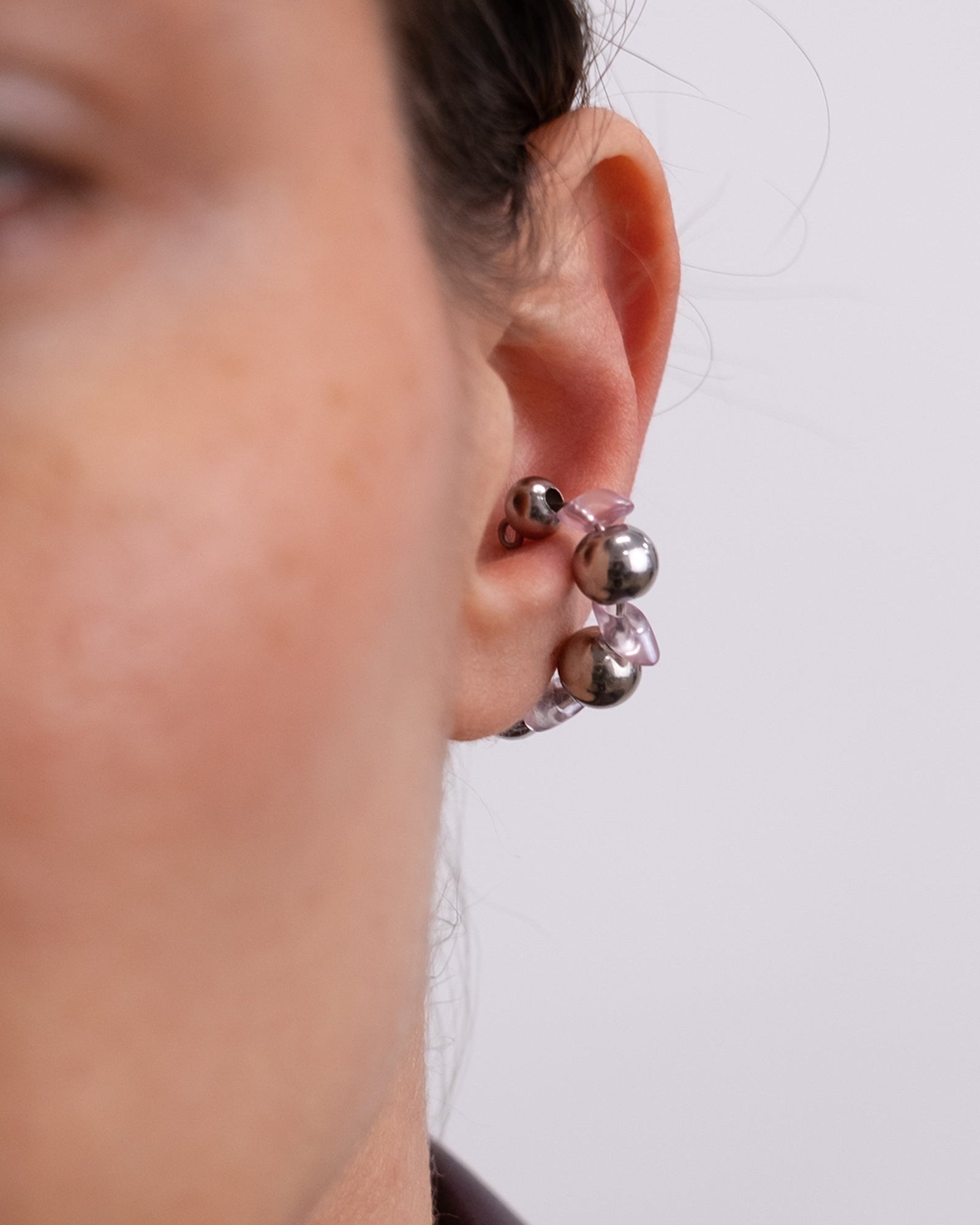 Earcuff en acier inoxydable. Il s’agit d’un faux piercing pour oreille non perçée qui se positionne au niveau du conch ou du lobe suivant la largeur de l’oreille. Il est composé d’un anneau argenté, avec des perles en verre de trois variantes de couleur et argentées.