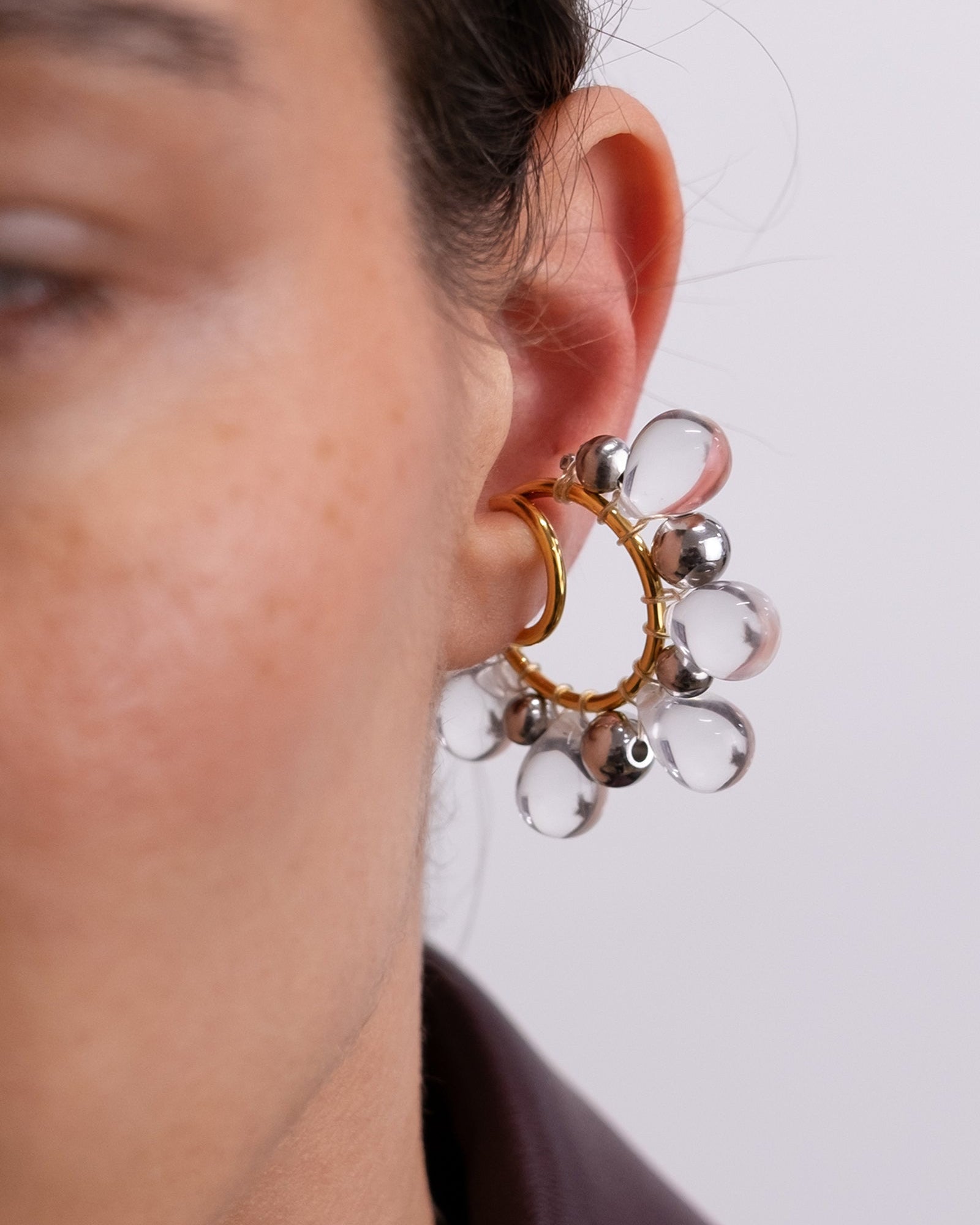 Il est composé d’un double anneau doré autour duquel sont tressées des perles en verre transparentes et des perles argentées de différentes tailles.