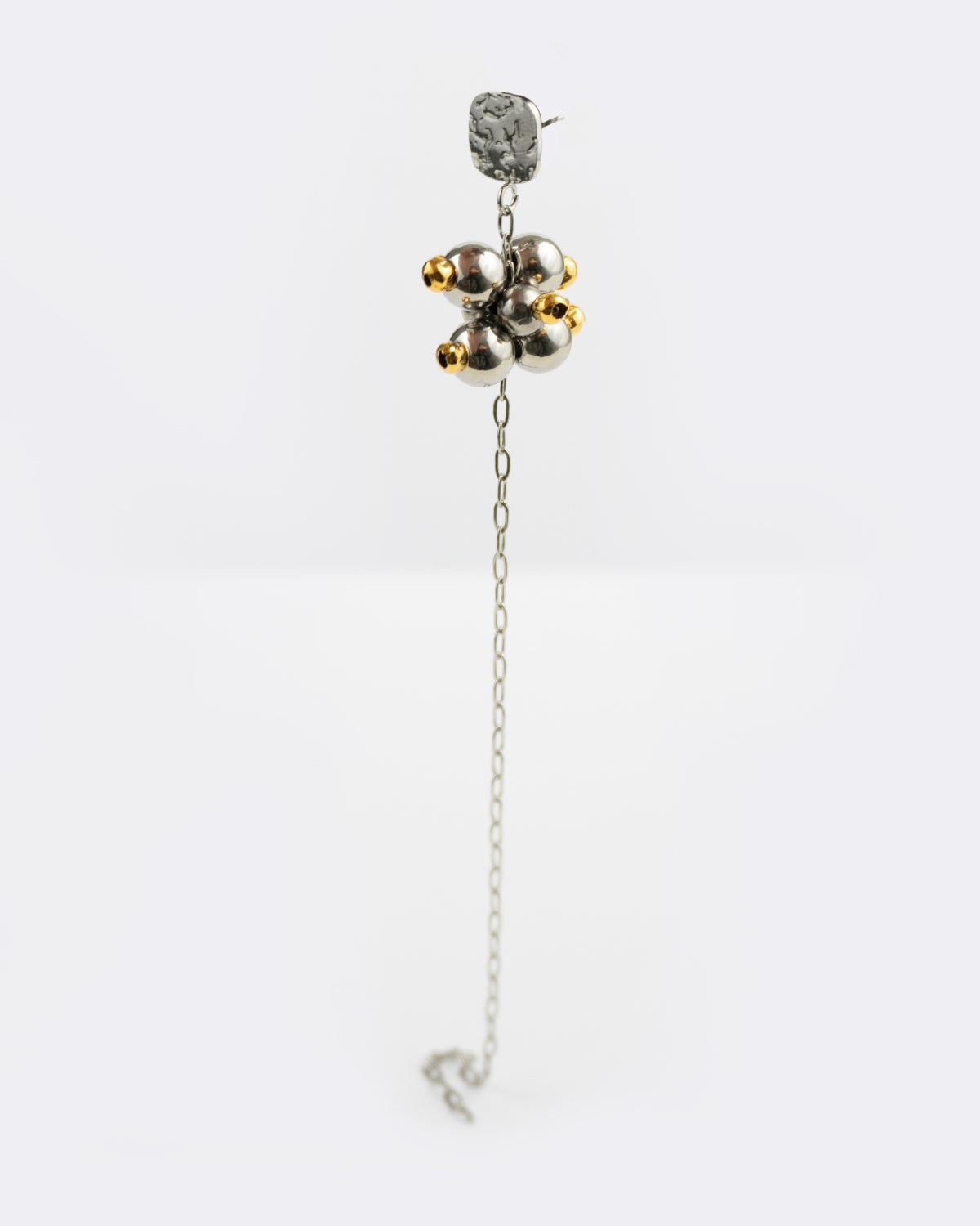 Mono boucle d’oreilles en acier inoxydable composée d’une puce d'oreilles argentée, d'une longue chaine argentée et d’une grappe de perles argentées et dorées dessus.