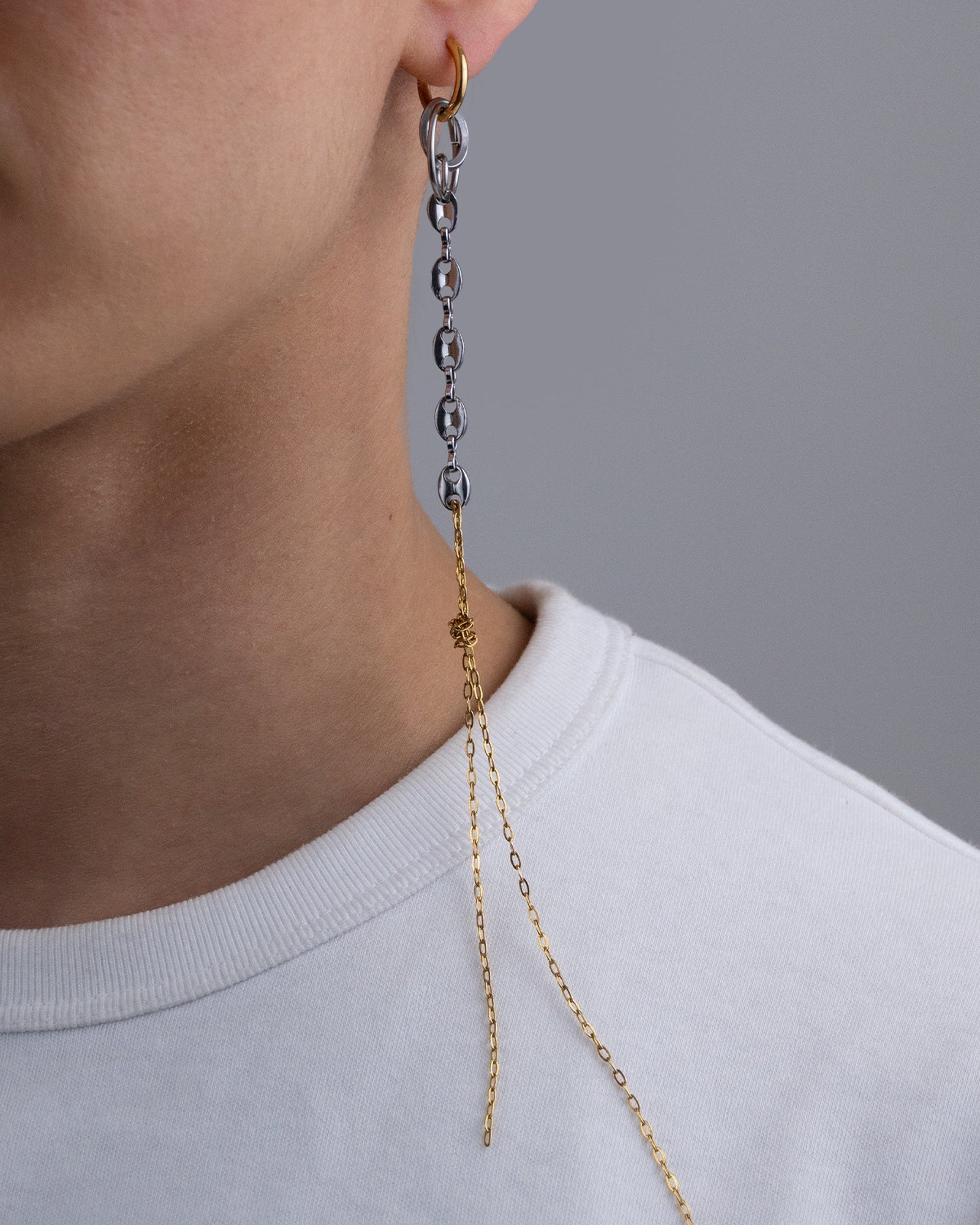 Mono boucle d’oreilles en acier inoxydable composée d’une créole dorée, d'anneaux argentés de différentes tailles, d'une chaine grain de café argentée et d'une chaine dorée nouée