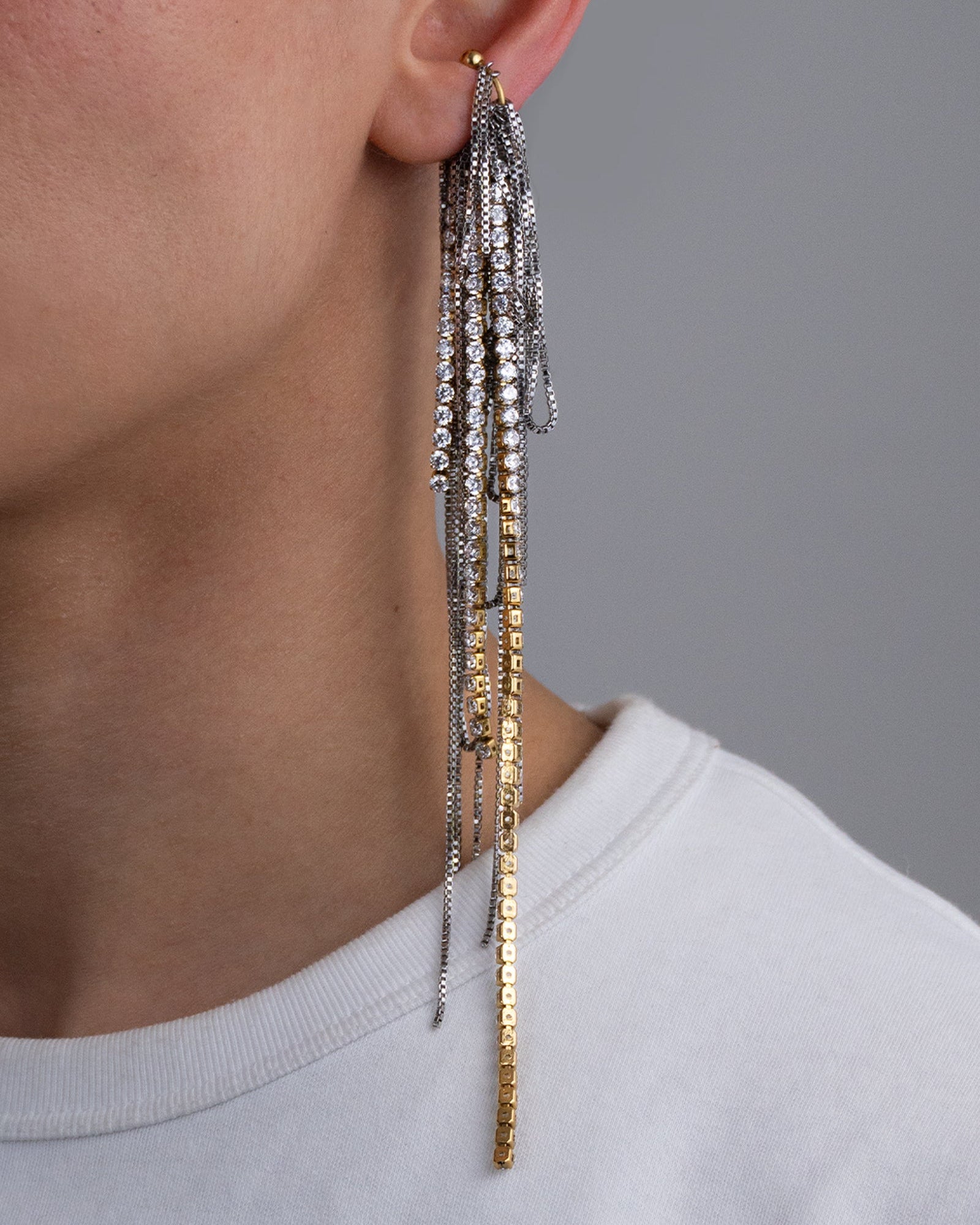 Earcuff en acier inoxydable. Il est composé d’un anneau doré et d’une multitude de chaines argentées de différentes longueurs et de chaines en strass.