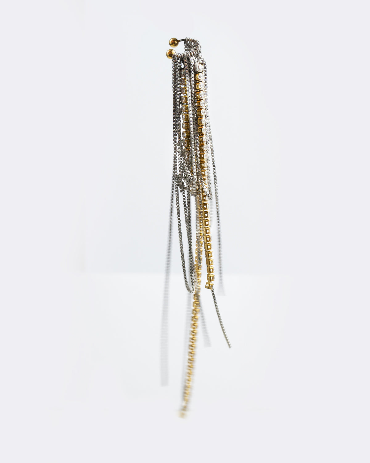 Earcuff en acier inoxydable. Il est composé d’un anneau doré et d’une multitude de chaines argentées de différentes longueurs et de chaines en strass.