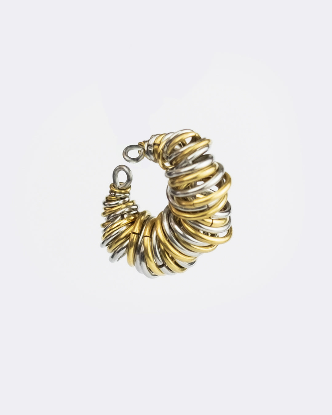 Earcuff en acier inoxydable. Il s’agit d’un faux piercing pour oreille non perçée qui se positionne au niveau du conch ou du lobe suivant la largeur de l’oreille. Il est composé d’un anneau argenté et d’une multitude d'anneaux doré et argenté de différents diamètres