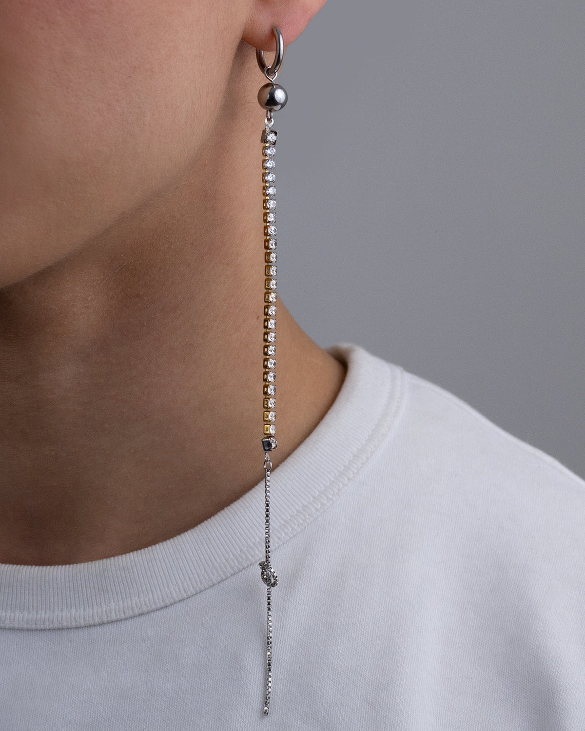 Mono boucle d’oreilles en acier inoxydable porté composée d’une créole argentée d’une perle argentée d’une chaîne en strass et d’une chaîne argentée