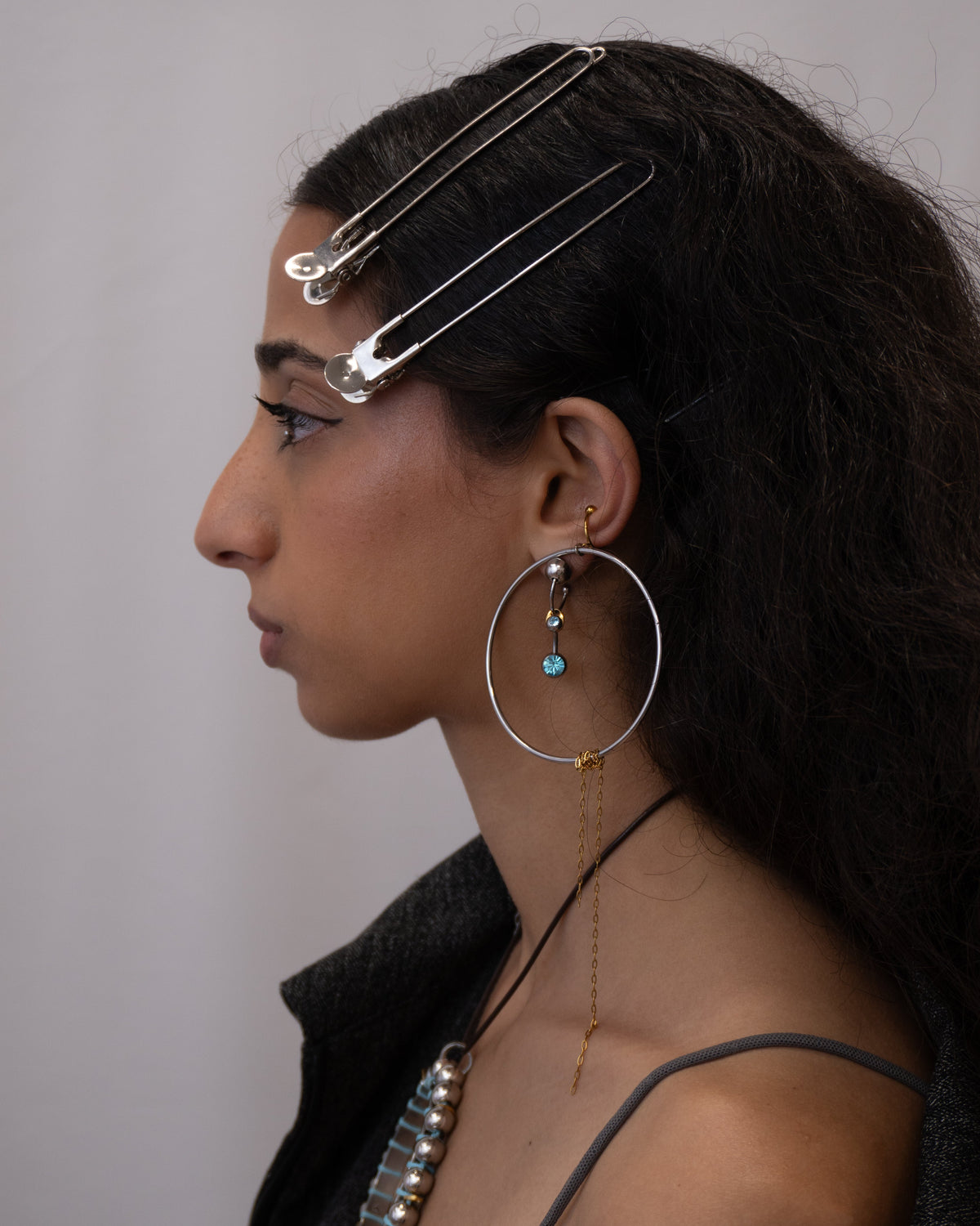 Mono boucle d’oreilles en acier inoxydable porté composée d’une demi-créole dorée ou argentée d’une perle argentée d’un grain de café doré et d’un piercing bleu
