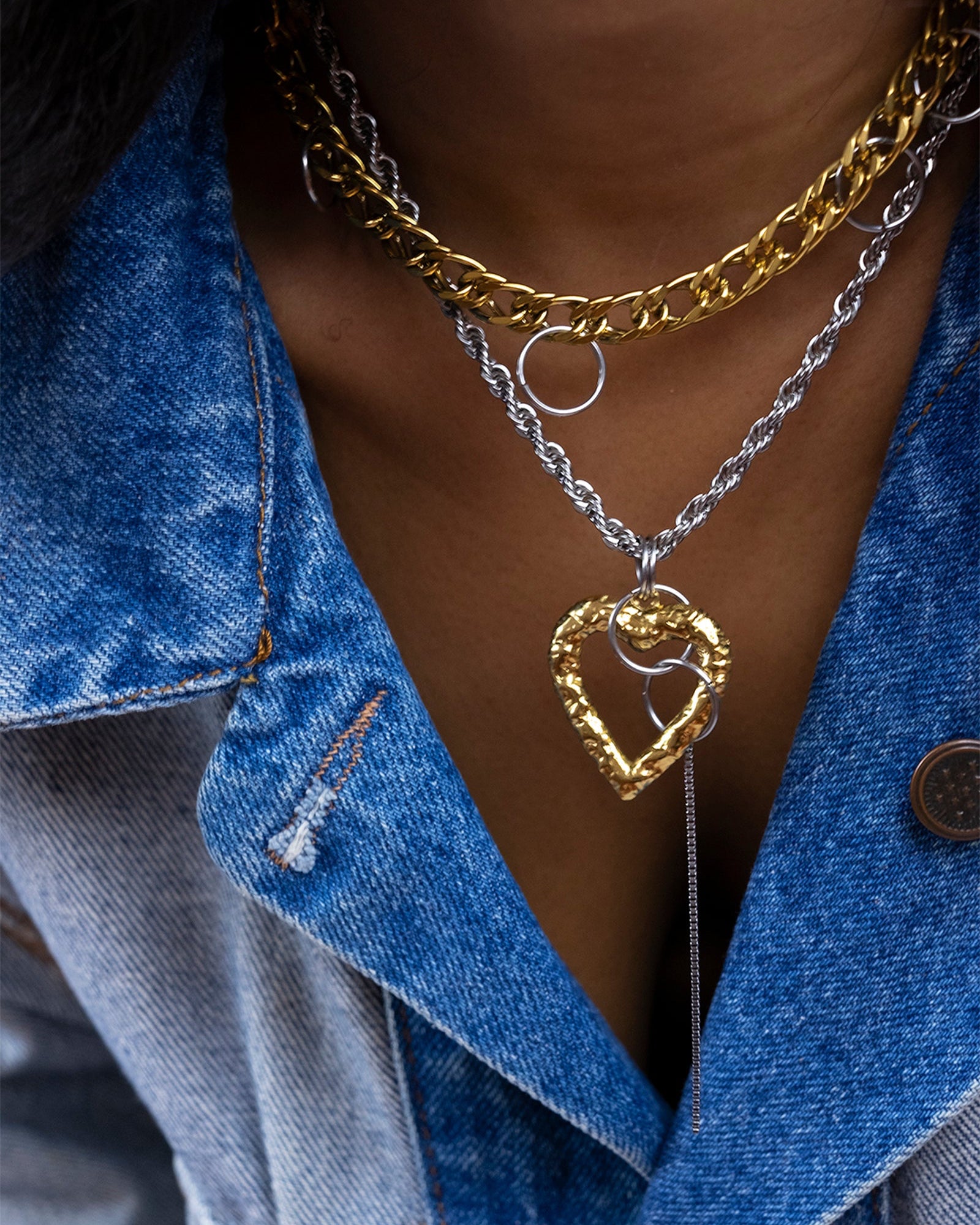 Collier en acier inoxydable avec une chaine doré et d'une chaine argenté qui peut se porter en version longue et en choker, avec un pendentif coeur martelé