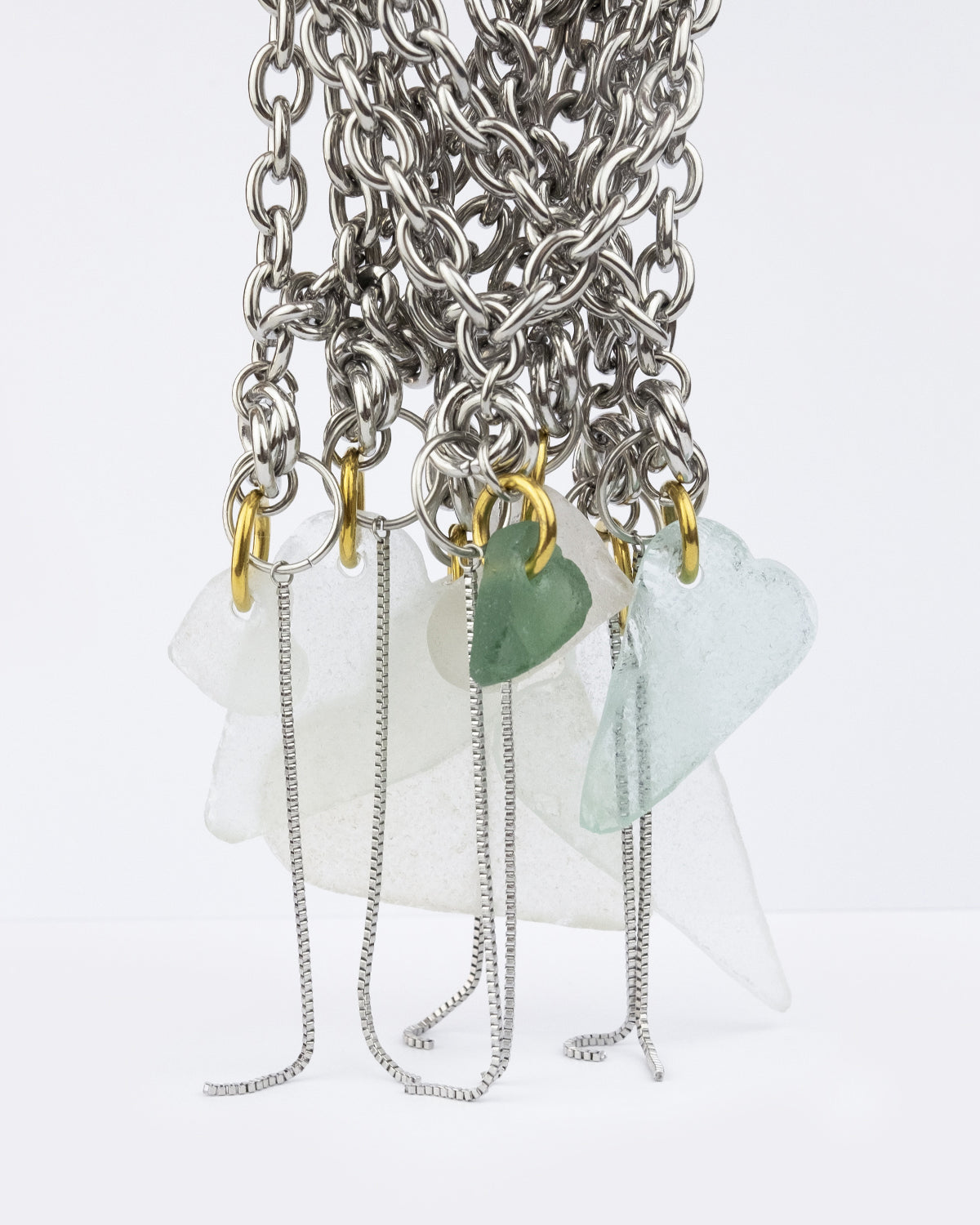 Collier en acier inoxydable. Il s'agit d'un collier ras de cou composé d'une chaine argenté et d'un morceau de verre poli ramassé sur la plage et façonné en forme de coeur.