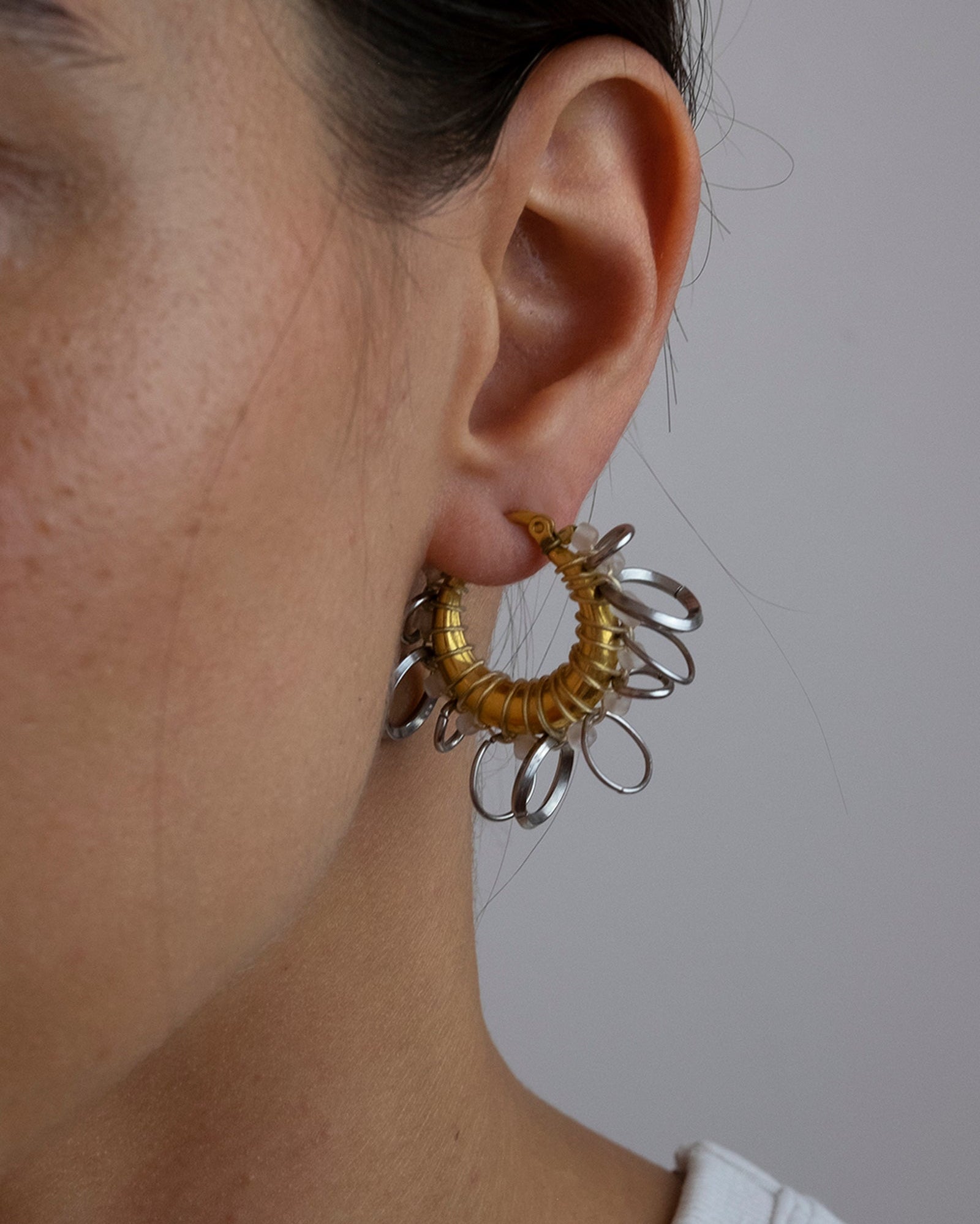 Mono boucle d’oreilles en acier inoxydable composée d’une créole doré, de perles de rocailles rose pâle et d'anneaux de multiples tailles argenté