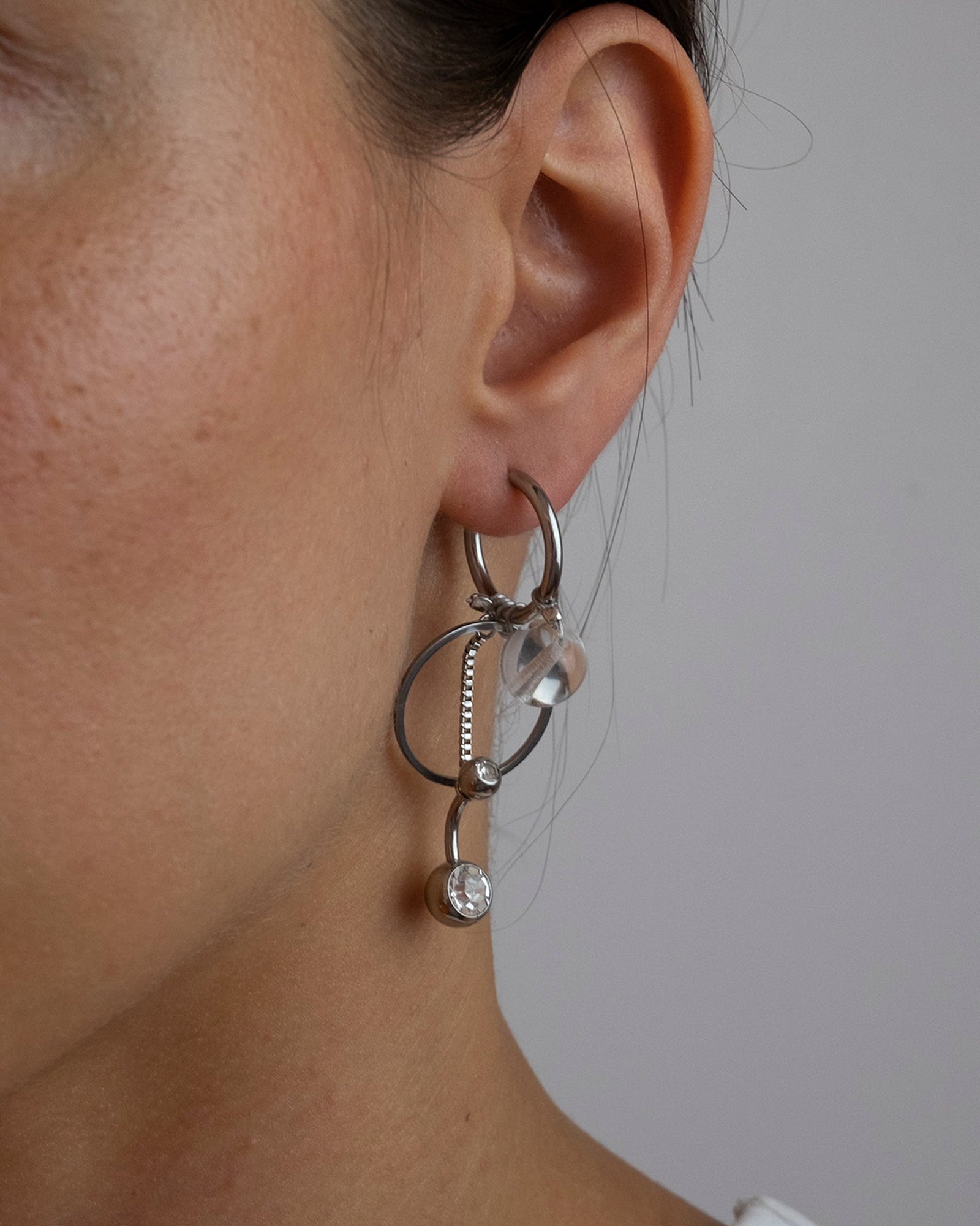 Mono boucle d’oreilles en acier inoxydable composée d’une créole argenté, d'une perles en verre, d'un anneau et d'une chaines pendante argenté avec un piercing au bout