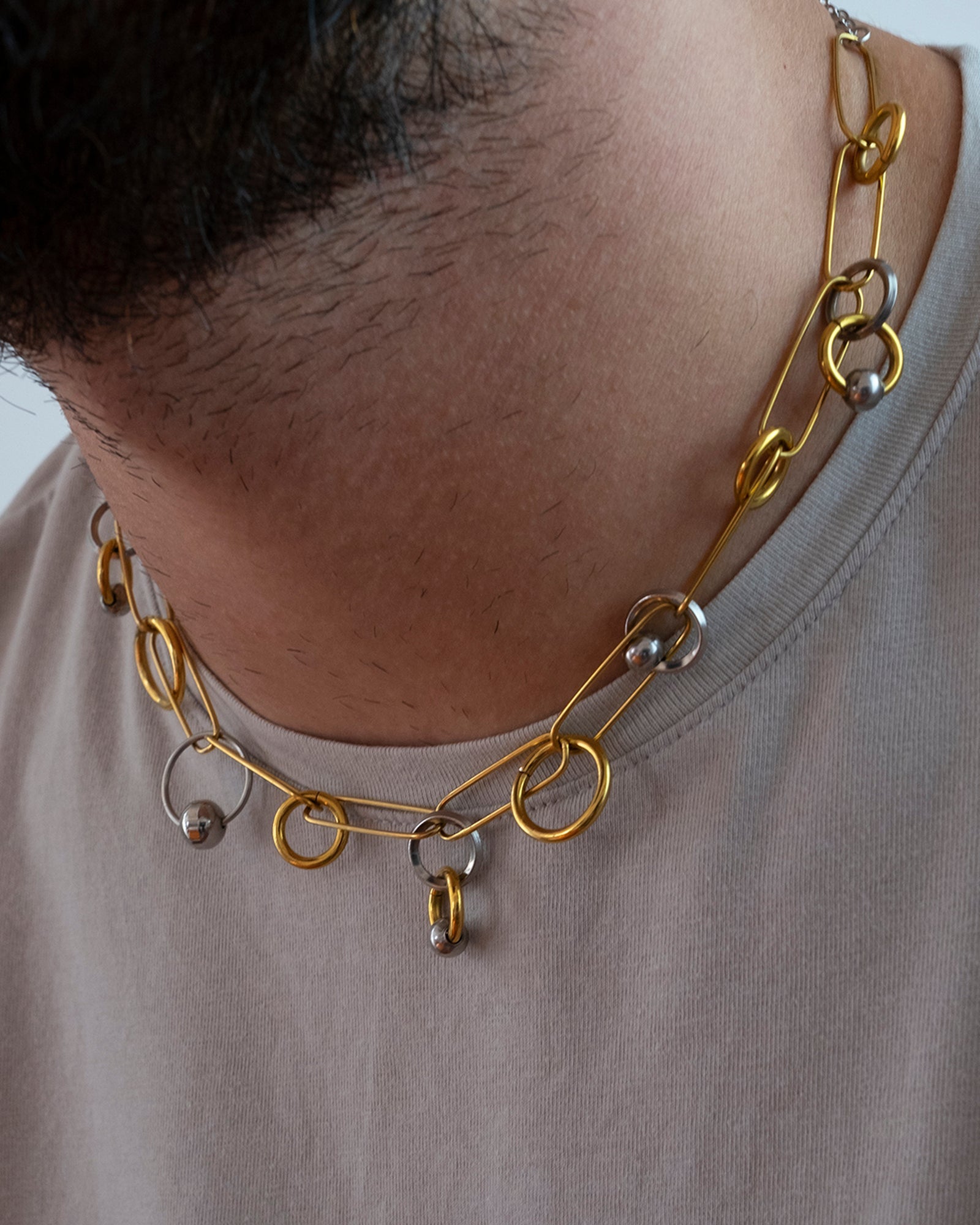 Collier en acier inoxydable. Il s'agit d'un collier composé d'une chaine doré entrelacée de plusieurs anneaux doré et argenté de différentes tailles et de différentes épaisseur