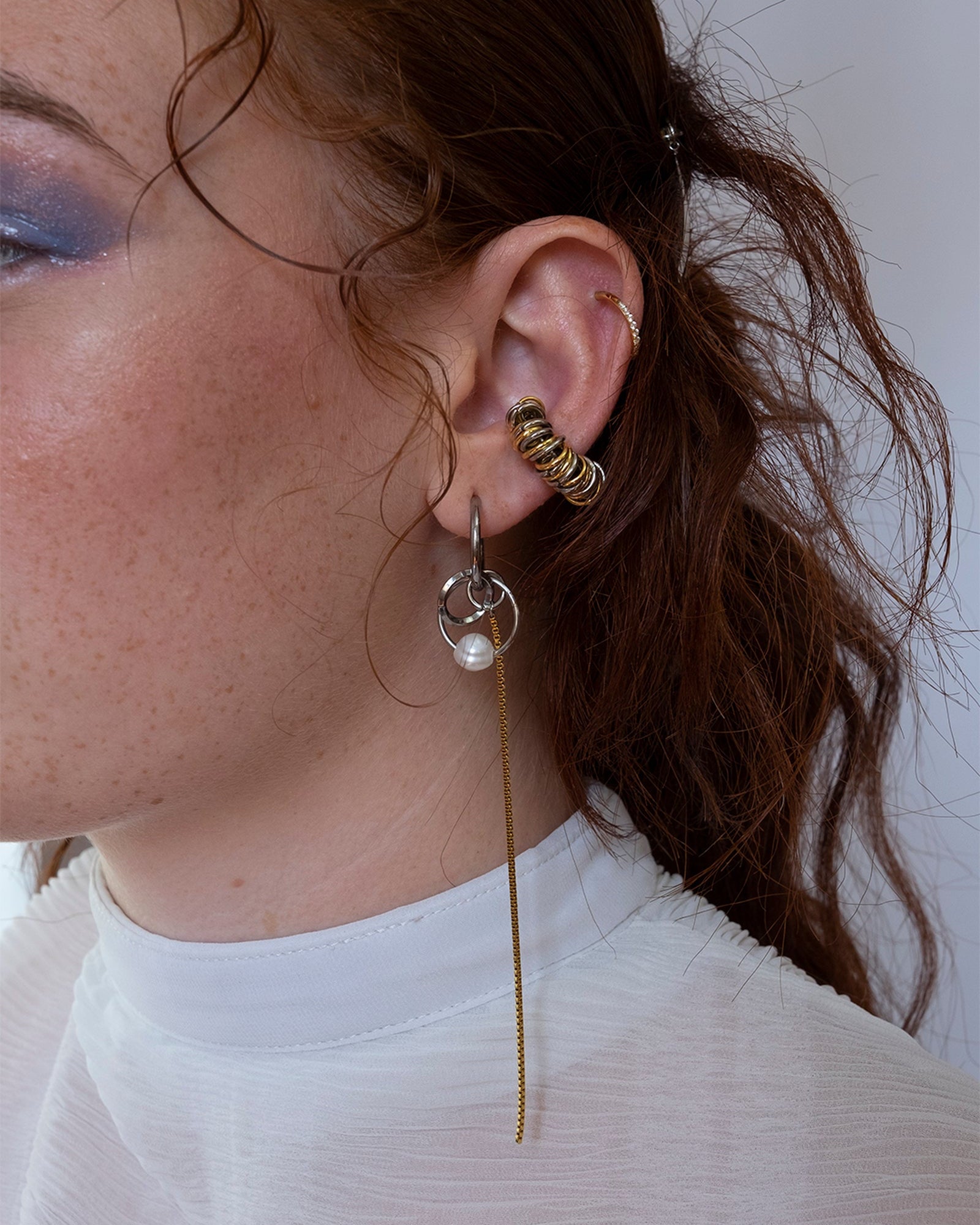 Mono boucle d’oreilles en acier inoxydable composée d’une créole argenté, d'anneaux argenté entremêlés et d'une perle de culture d'eau douce