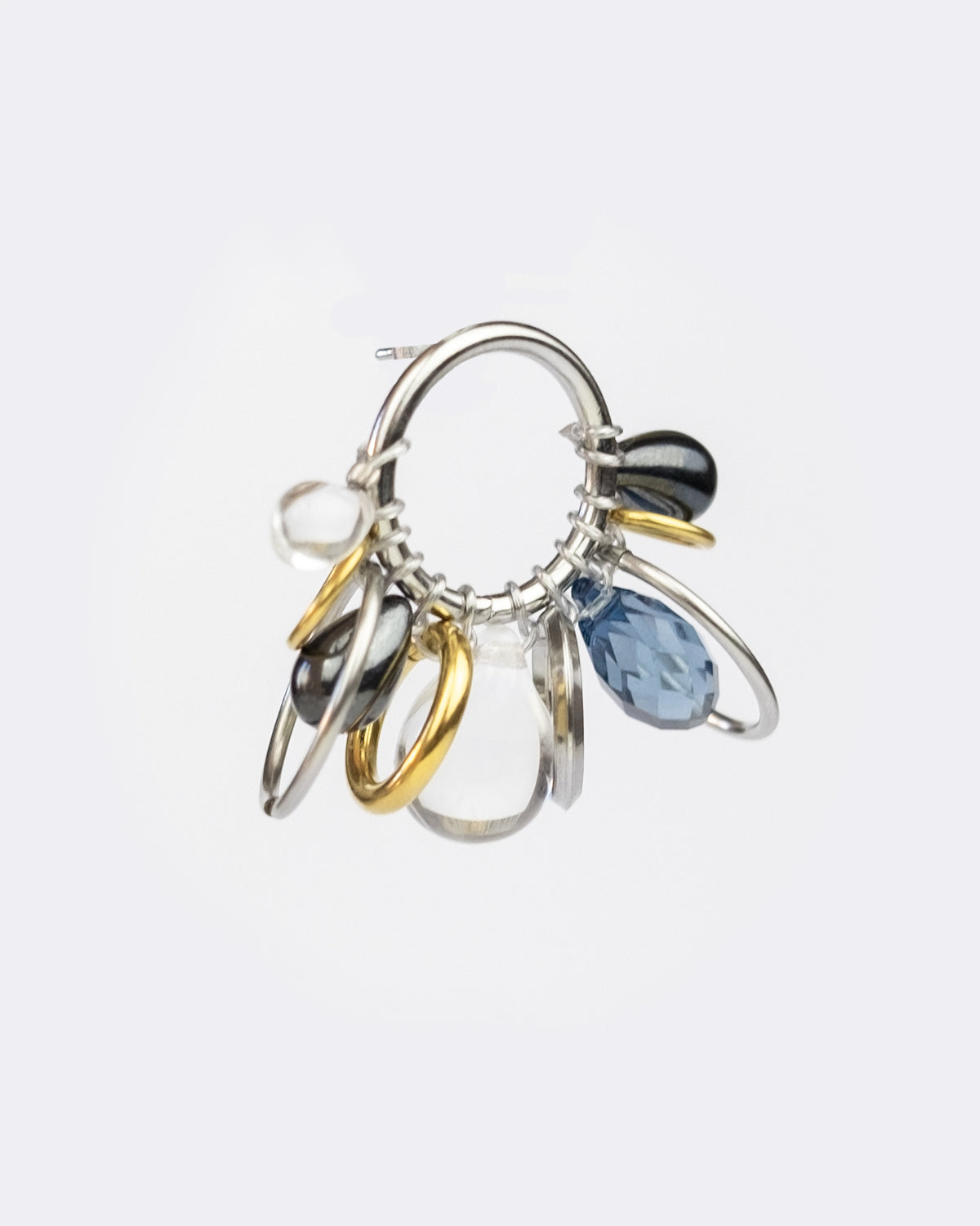Mono boucle d’oreilles en acier inoxydable composée d’une mono boucle d’oreilles puce argenté, d'anneaux argenté et doré et différentes tailles des épaisseurs ainsi que de perles variées en verre et hématite en forme de goutte