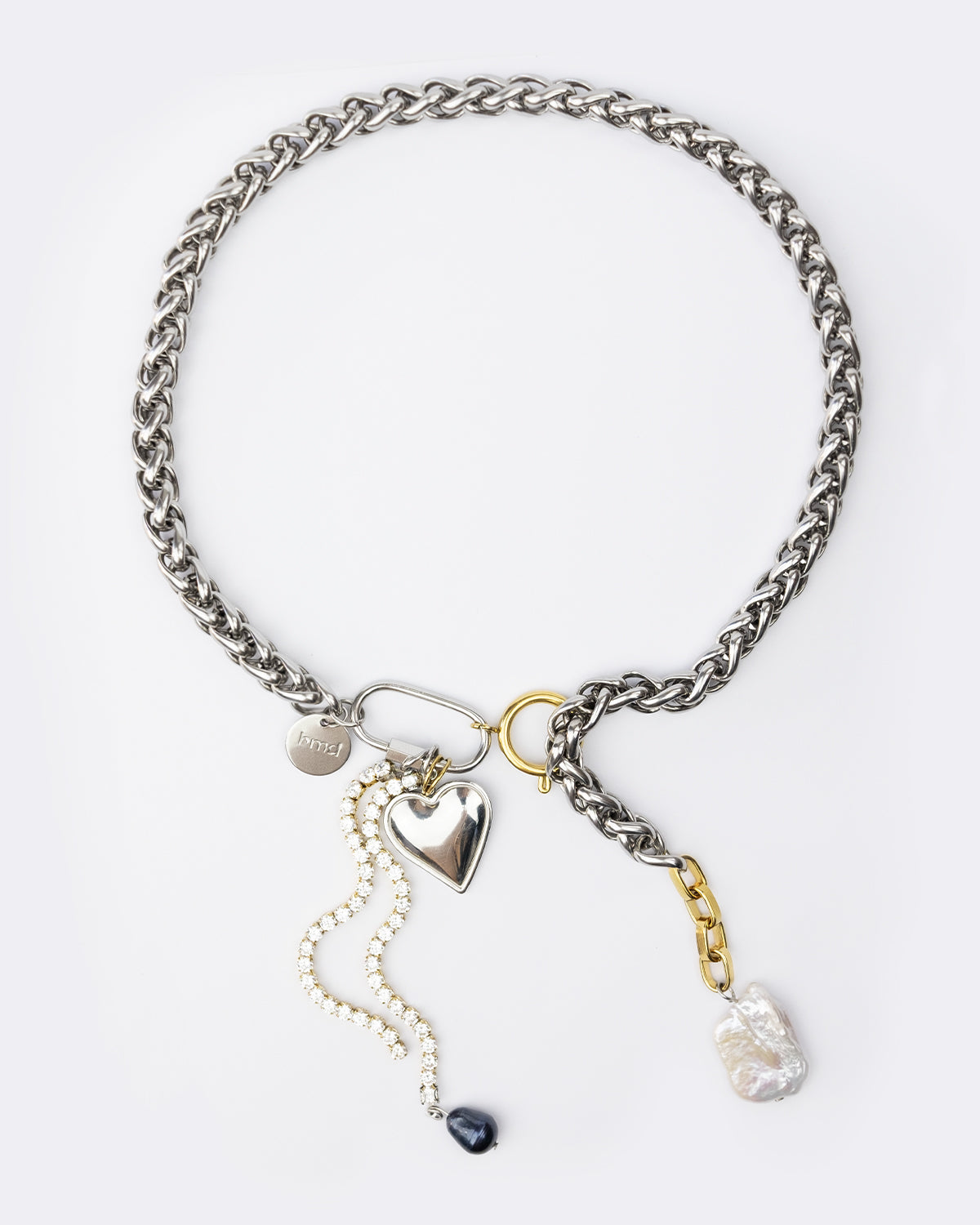 Collier en acier inoxydable . Il s'agit d'un collier composé d'une chaine argentée avec deux mousquetons à l'avant contenant un pendentif coeur argenté et deux chaine en strass avec une perle de culture d'eau douce noire sur l'une d'elle