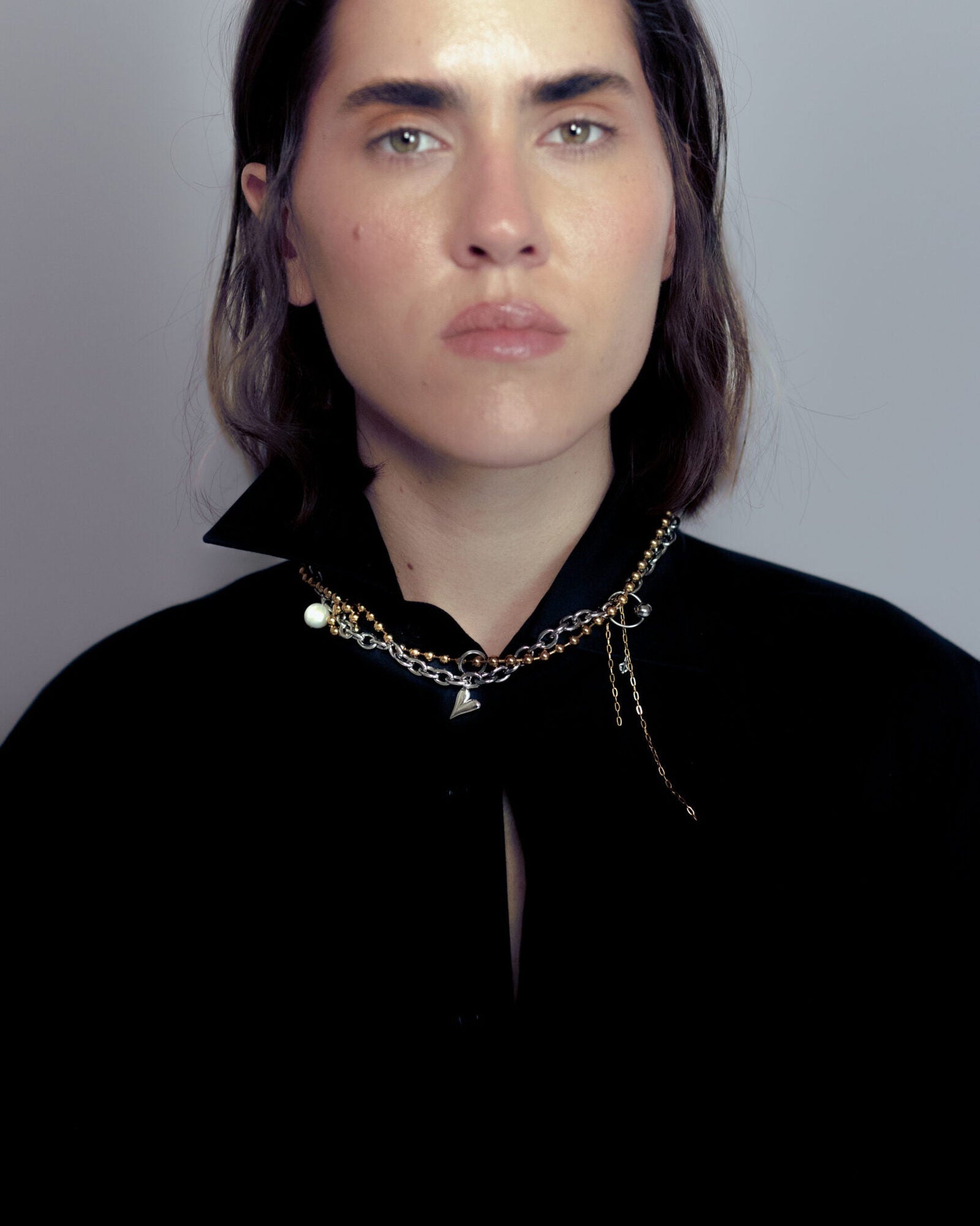 Collier en acier inoxydable . Il s'agit d'un collier composé d'une chaine bille dorée et d'une chaine argentée entremêlée, agrémentées d'un pendentif coeur et d'une perle de culture d'eau douce