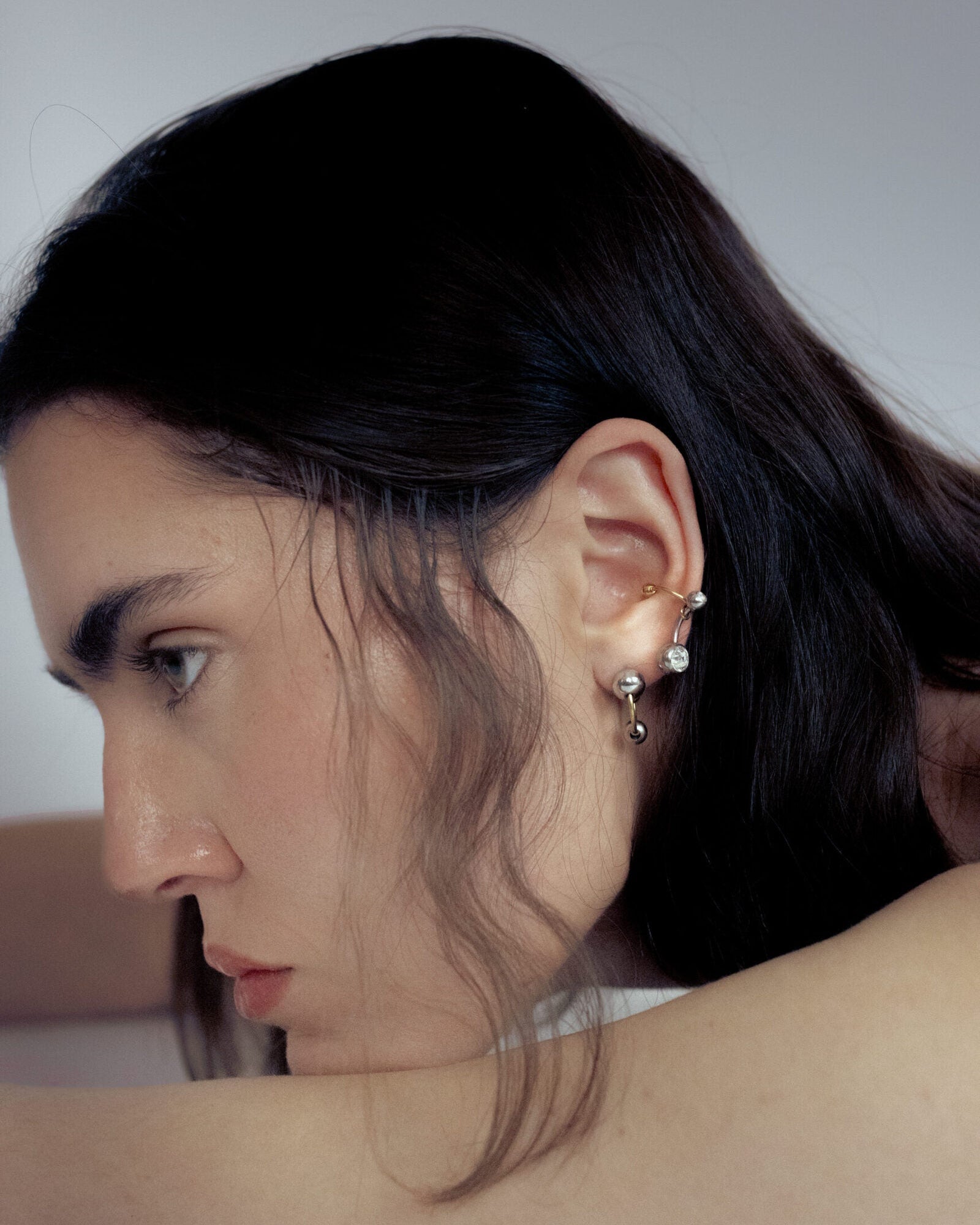 Mono boucle d’oreilles en acier inoxydable composée d’une demi-créole dorée et de deux perles argentées de différentes tailles