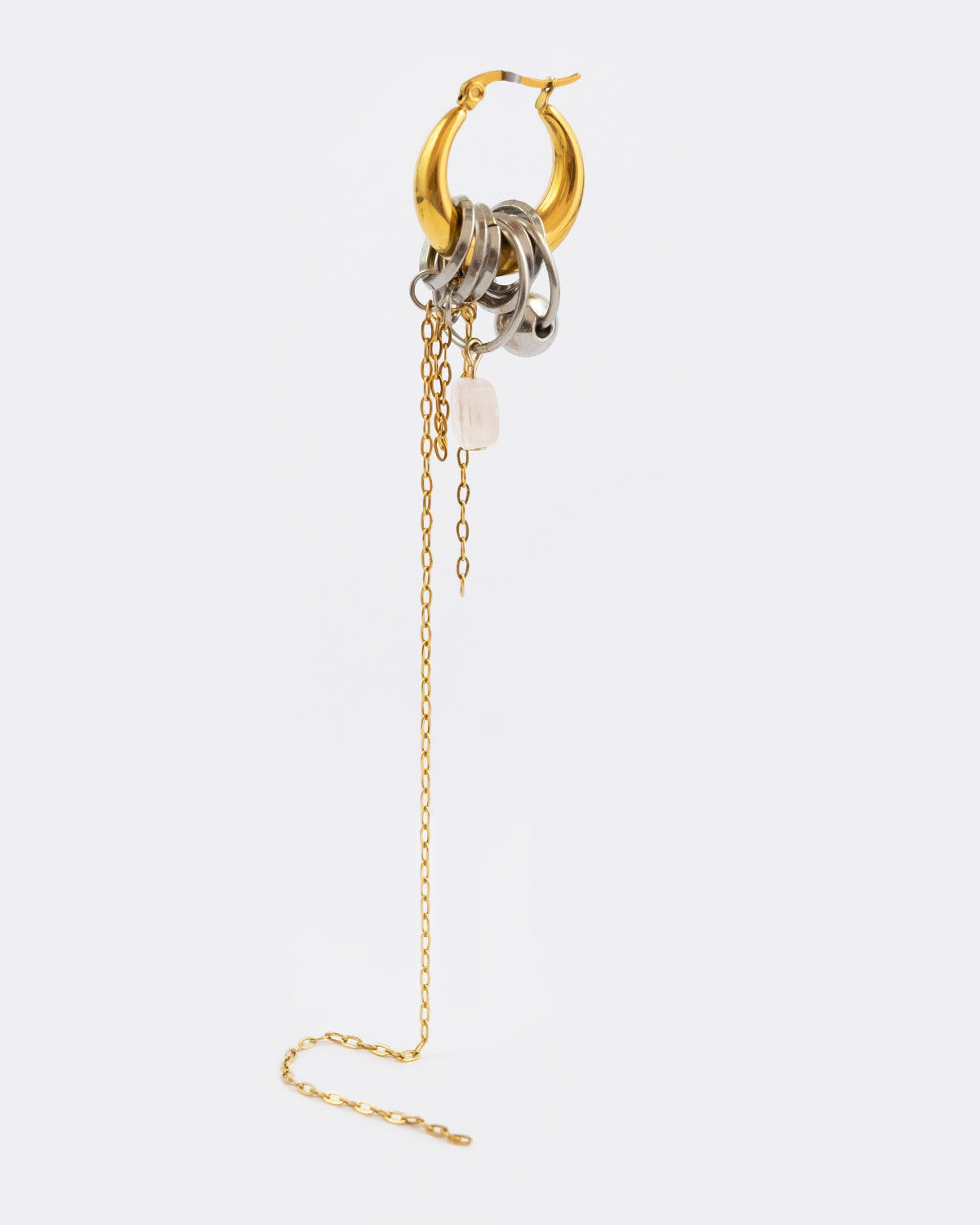 Mono boucle d’oreilles en acier inoxydable composée d’une créole dorée, d'anneaux argentés, d'une pierre en quartz rose et d'une chaine pendante doré