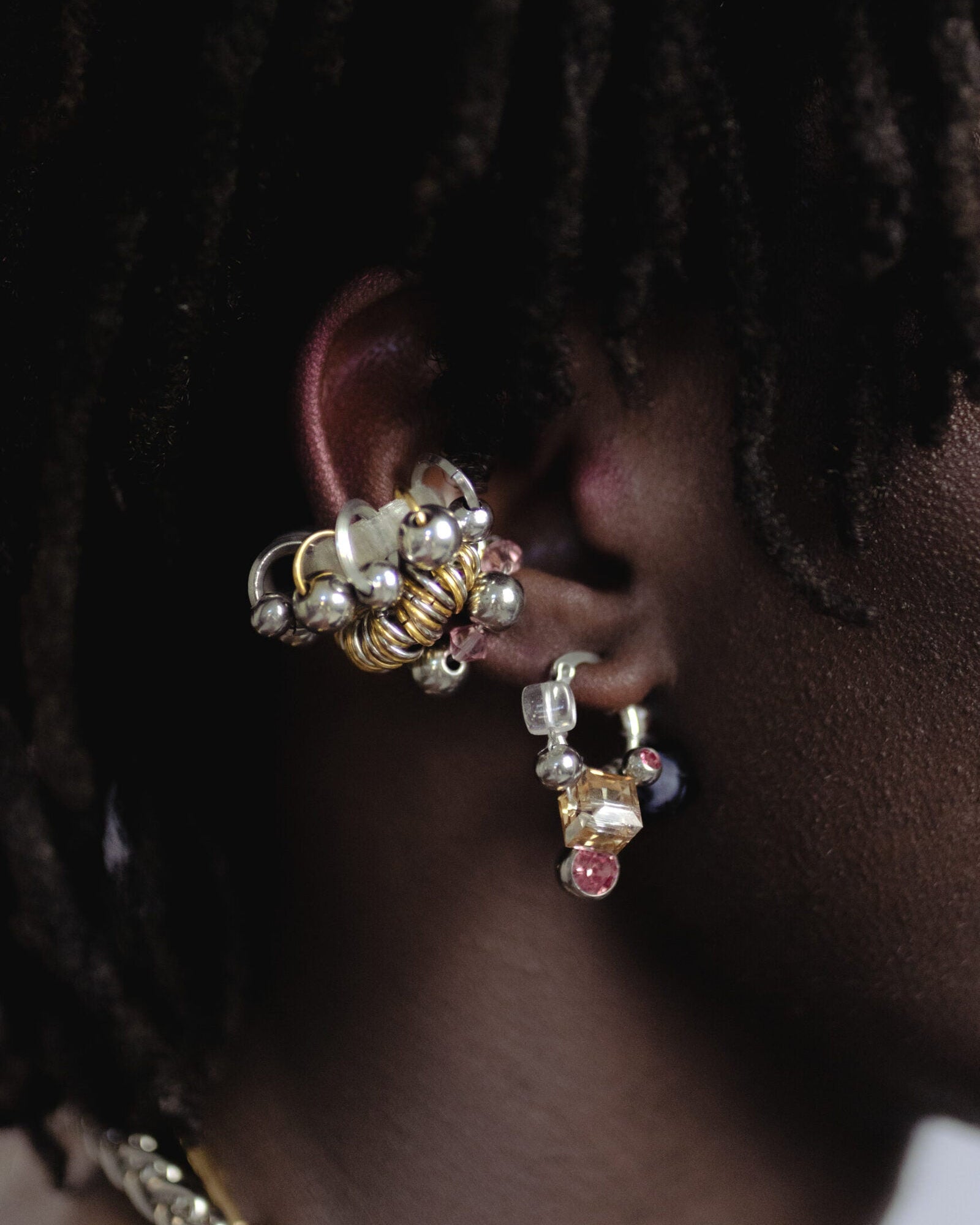 Mono boucle d’oreilles en acier inoxydable composée d’une créole argentée, de perles en cristal, en verre, et synthétique, ainsi qu'un piercing, tressés autour de la boucle