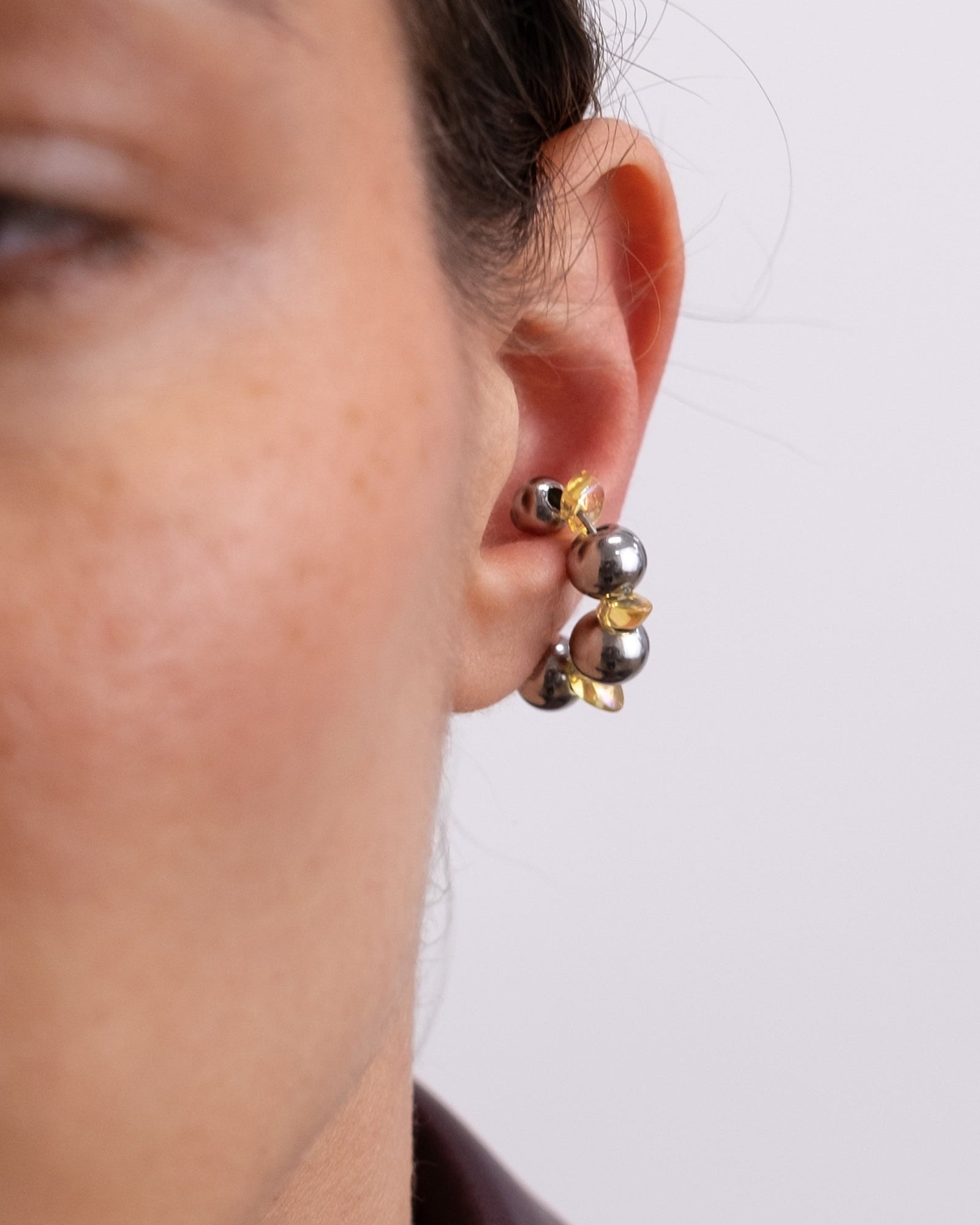Earcuff en acier inoxydable. Il s’agit d’un faux piercing pour oreille non perçée qui se positionne au niveau du conch ou du lobe suivant la largeur de l’oreille. Il est composé d’un anneau argenté, avec des perles en verre de trois variantes de couleur et argentées.
