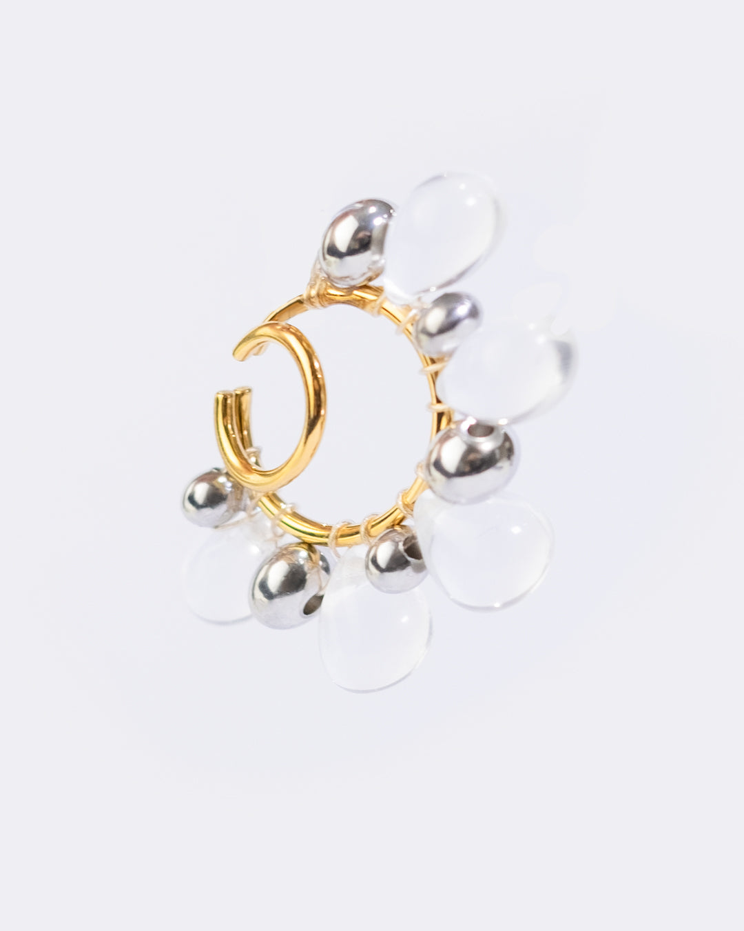 Il est composé d’un double anneau doré autour duquel sont tressées des perles en verre transparentes et des perles argentées de différentes tailles.