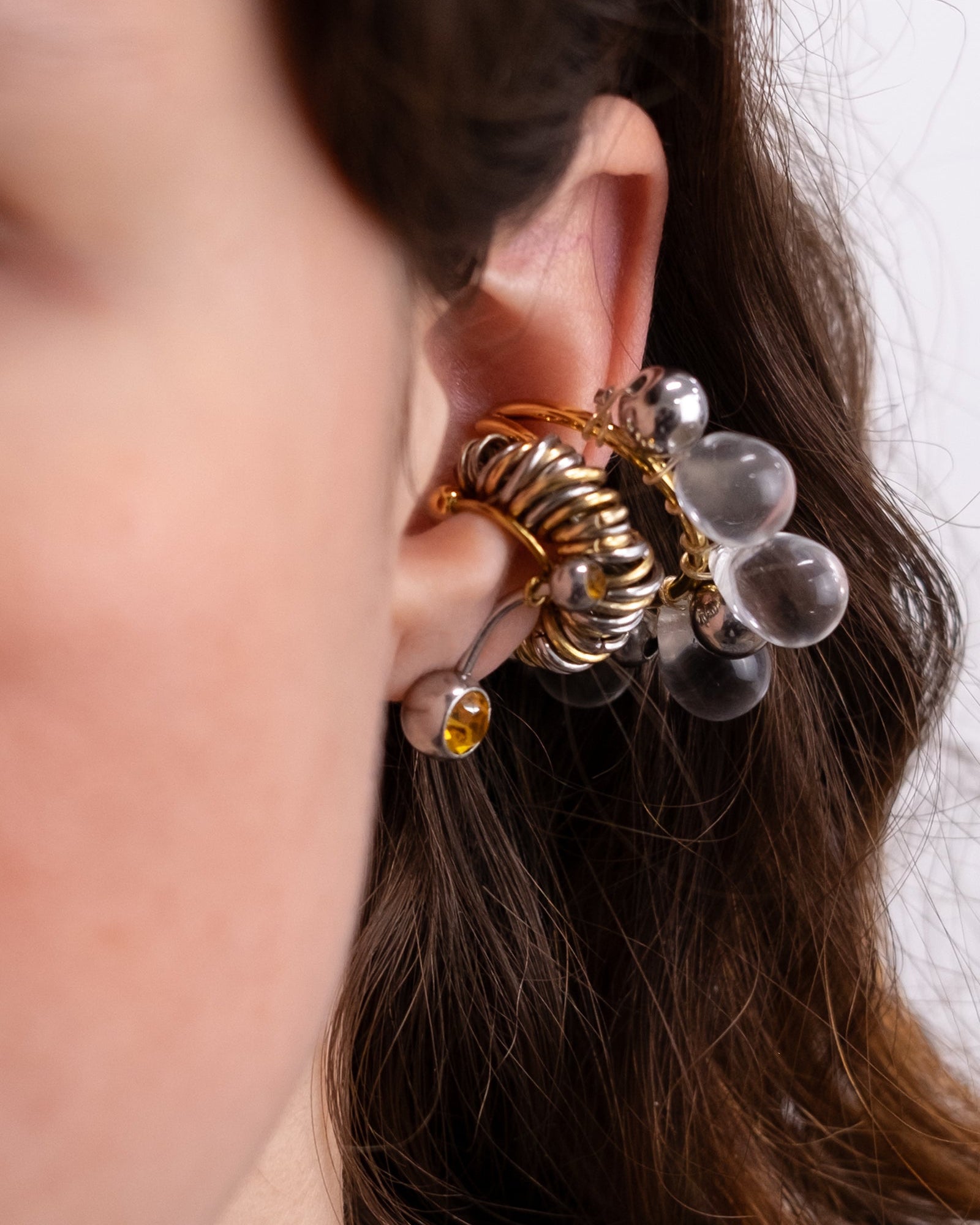 Earcuff en acier inoxydable. Il s’agit d’un faux piercing pour oreille non perçée qui se positionne au niveau du conch ou du lobe suivant la largeur de l’oreille. Il est composé d’un anneau doré et d'un piercing de couleur.