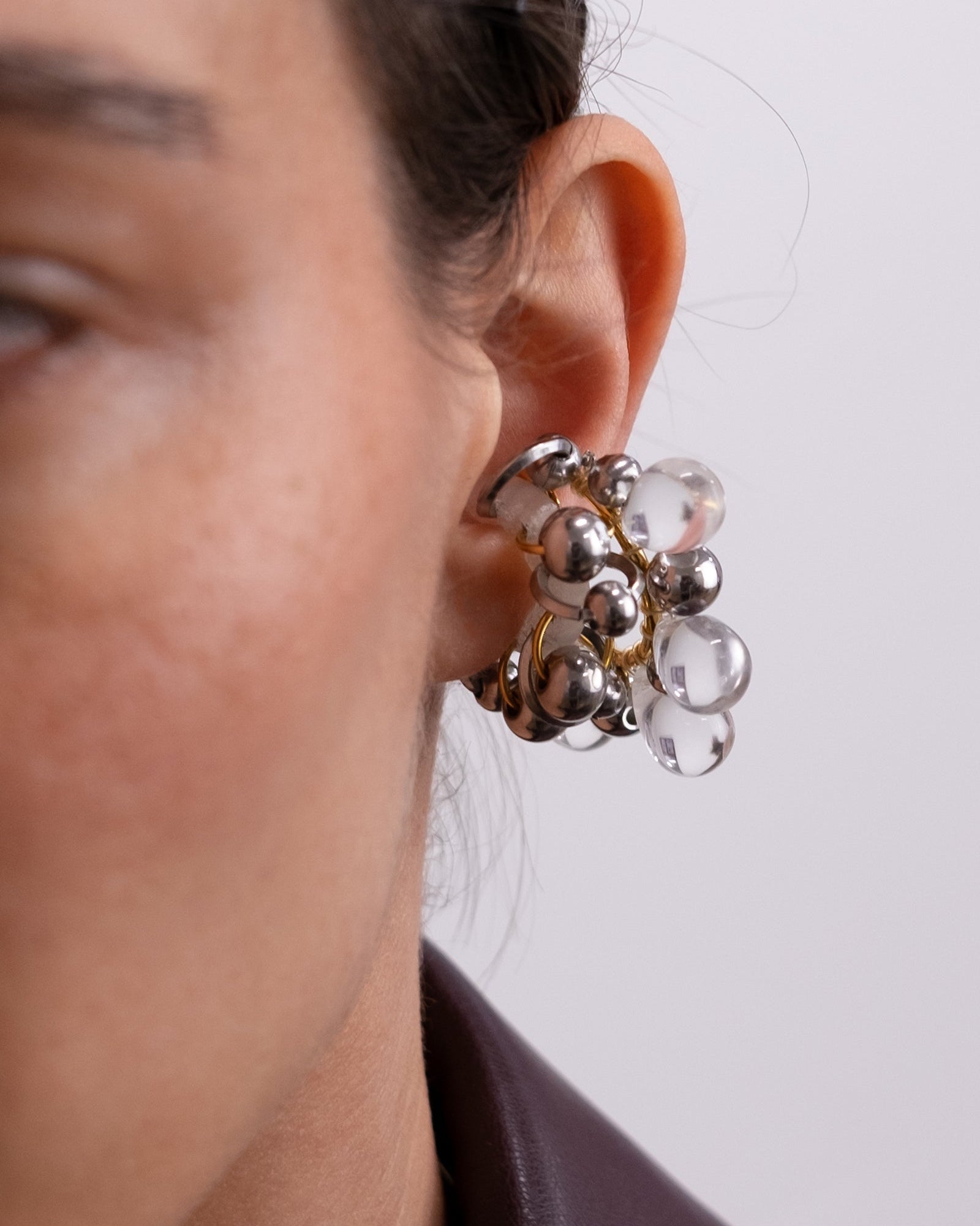 Il est composé d’un double anneau doré autour duquel sont tressées des perles en verre transparentes et des perles argentées de différentes tailles.