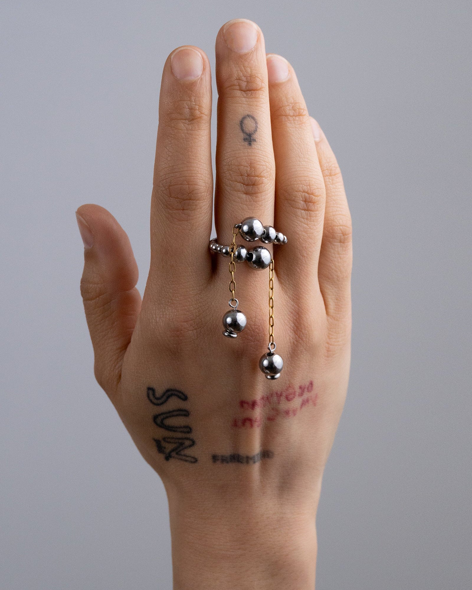 Bague en acier inoxydable composée de perles argentée et de chaines pendantes dorées. Cette bague est réglable et disponible en deux tailles : - 48 à 54 - 54 à 62