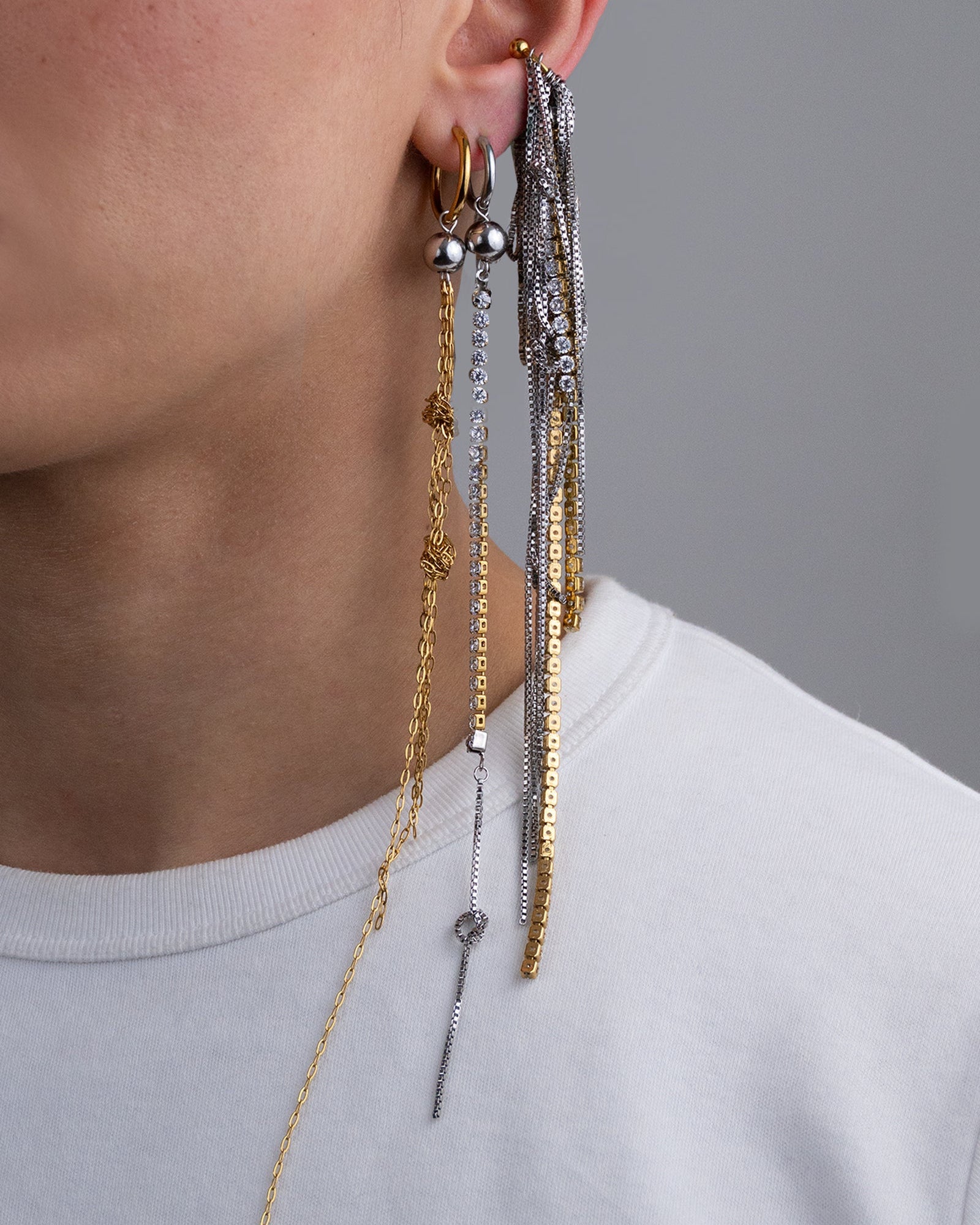 Earcuff en acier inoxydable. Il est composé d’un anneau doré et d’une multitude de chaines argentées de différentes longueurs et de chaines en strass.