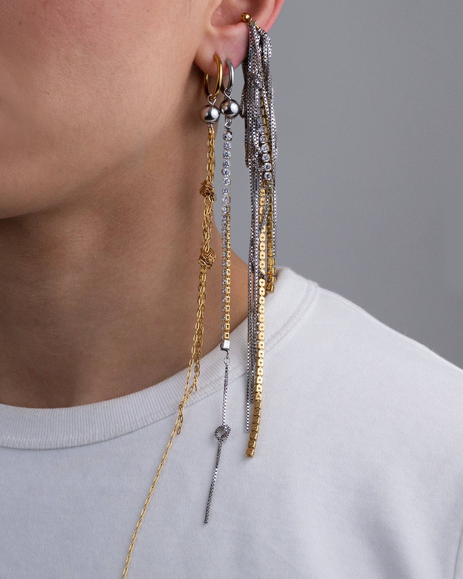 Earcuff en acier inoxydable. Il est composé d’un anneau doré et d’une multitude de chaines argentées de différentes longueurs et de chaines en strass.