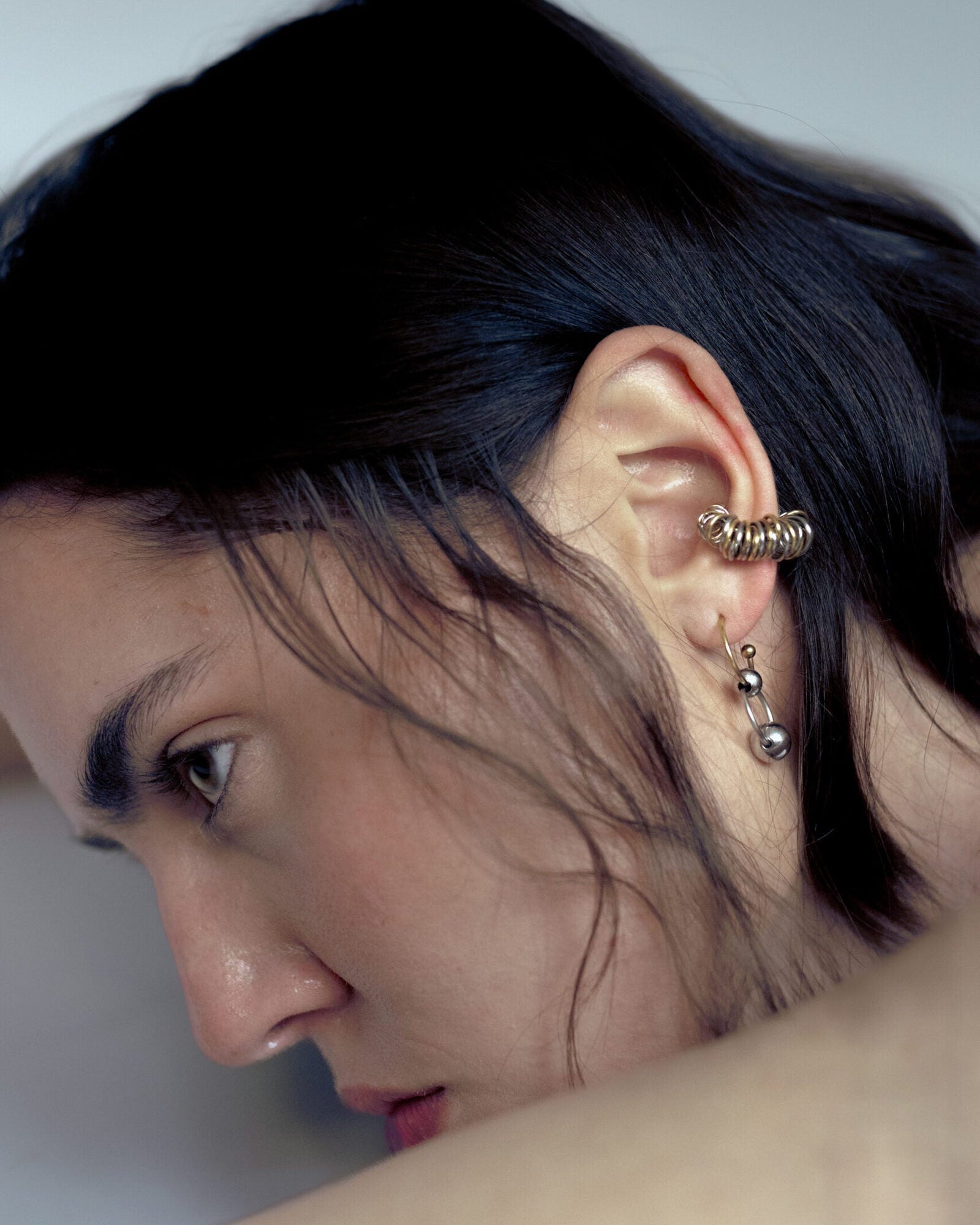 Mono boucle d’oreilles en acier inoxydable composée d’une demi-créole dorée et de deux perles argentées de différentes tailles