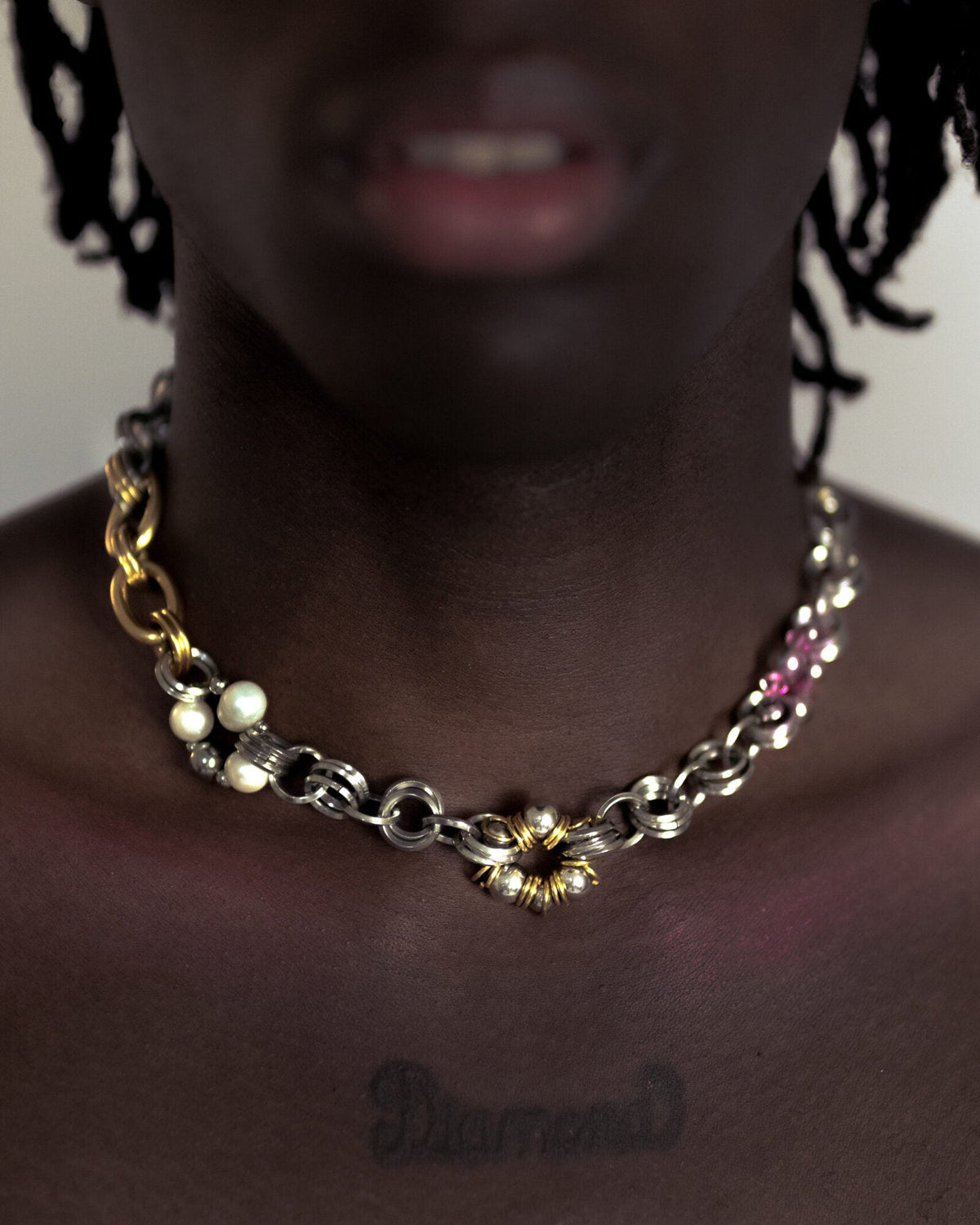 Collier en acier inoxydable porté composé d'une chaîne argentée et de deux chaînes dorées plus ou moins épaisses séparées par des éléments ronds perlés faisant penser à nos earcuffs