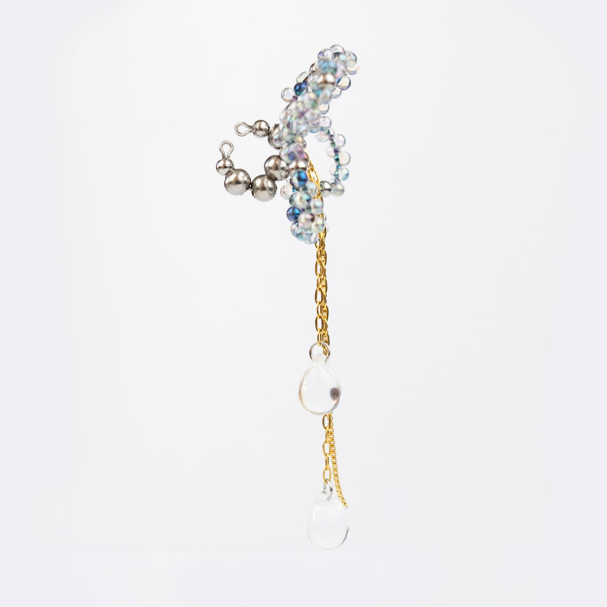 Earcuff en acier inoxydable composé d'un anneau argenté, d'une sculpture en perles en verre en forme de fleur et d'une chaîne dorée avec des perles gouttes au bout