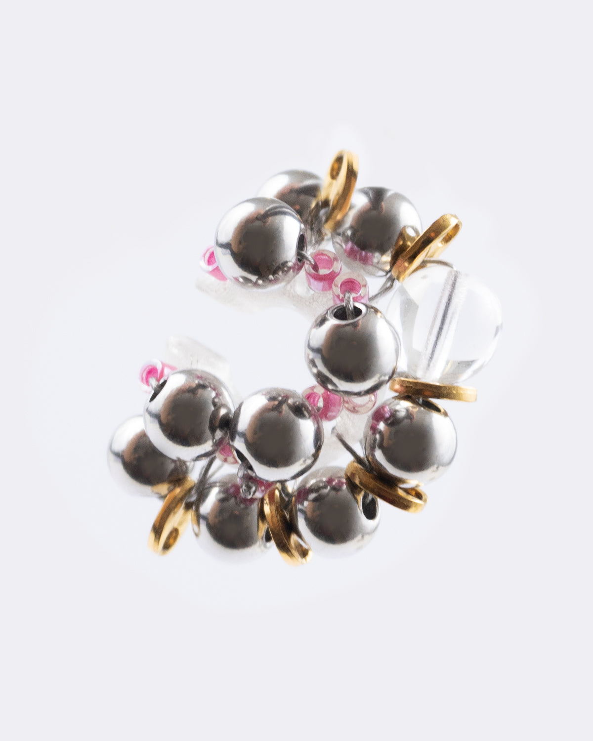 Earcuff Jelly Duo Rose porté en plastique biosourcé composé d'une multitude de perles argentées de grains de café dorés et de perles en verre colorées roses tressés sur une base transparente