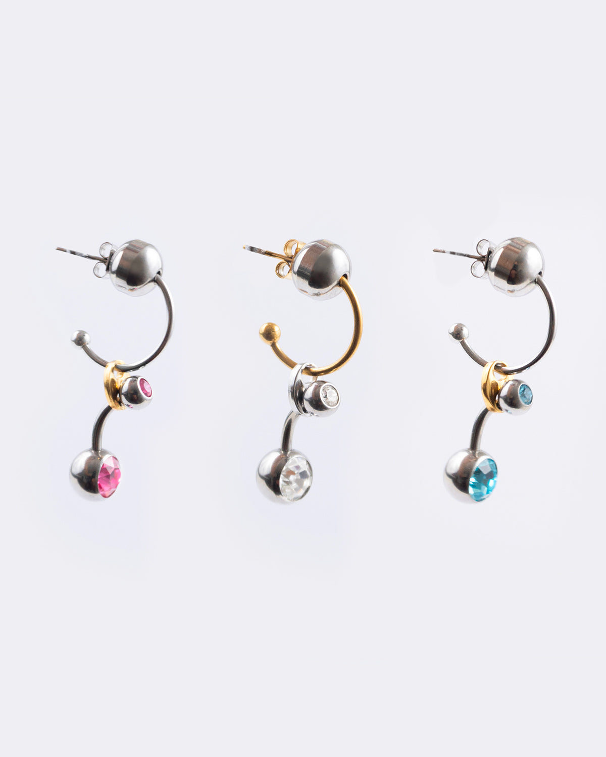 Gamme mono boucle d’oreilles en acier inoxydable composée d’une demi-créole dorée ou argentée d’une perle argentée, d’un grain de café doré et d’un piercing rose blanc ou bleu