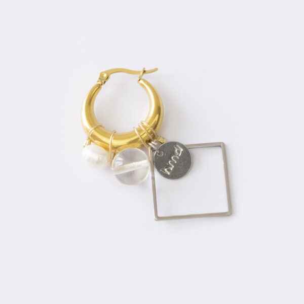 Mono boucle d’oreilles en acier inoxydable composée d’une créole doré, d'une perle de culture d'eau douce, d'une perle en verre transparente et d'un apprêt ainsi que d'un médaillon estampé de la marque argenté