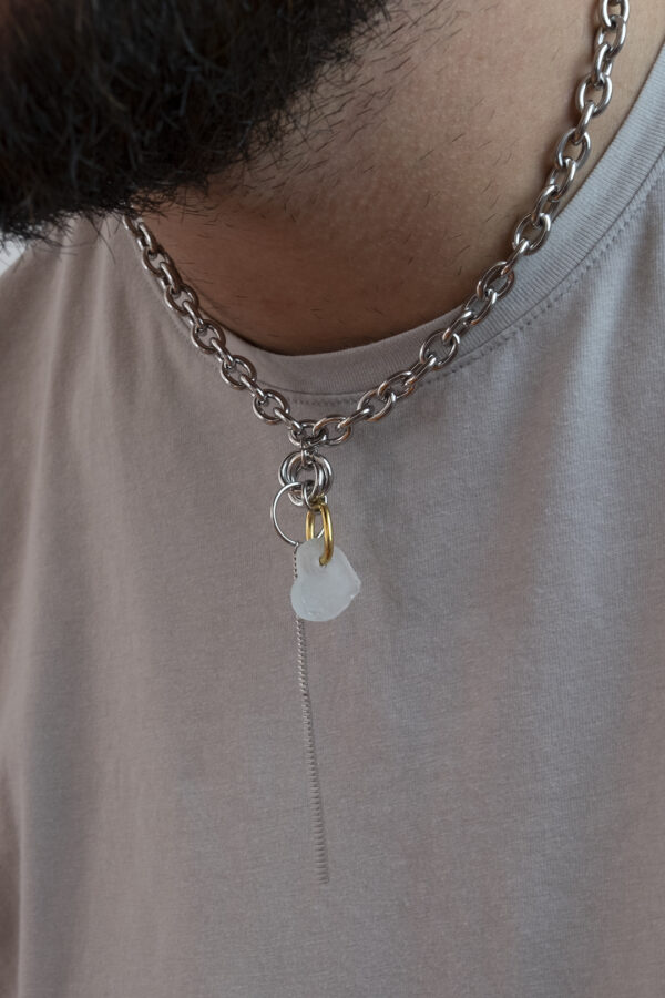 Collier en acier inoxydable. Il s'agit d'un collier ras de cou composé d'une chaine argenté et d'un morceau de verre poli ramassé sur la plage et façonné en forme de coeur.