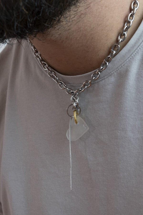 Collier en acier inoxydable. Il s'agit d'un collier ras de cou composé d'une chaine argenté et d'un morceau de verre poli ramassé sur la plage et façonné en forme de coeur.