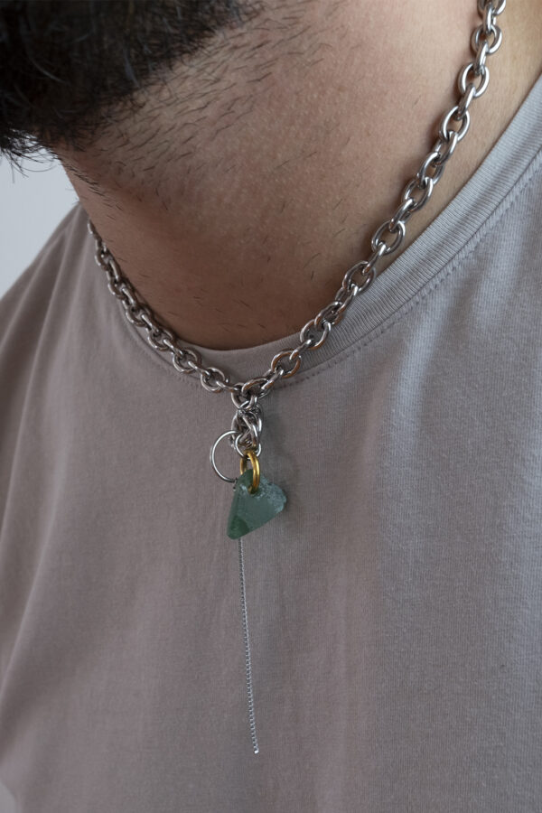 Collier en acier inoxydable. Il s'agit d'un collier ras de cou composé d'une chaine argenté et d'un morceau de verre poli ramassé sur la plage et façonné en forme de coeur.