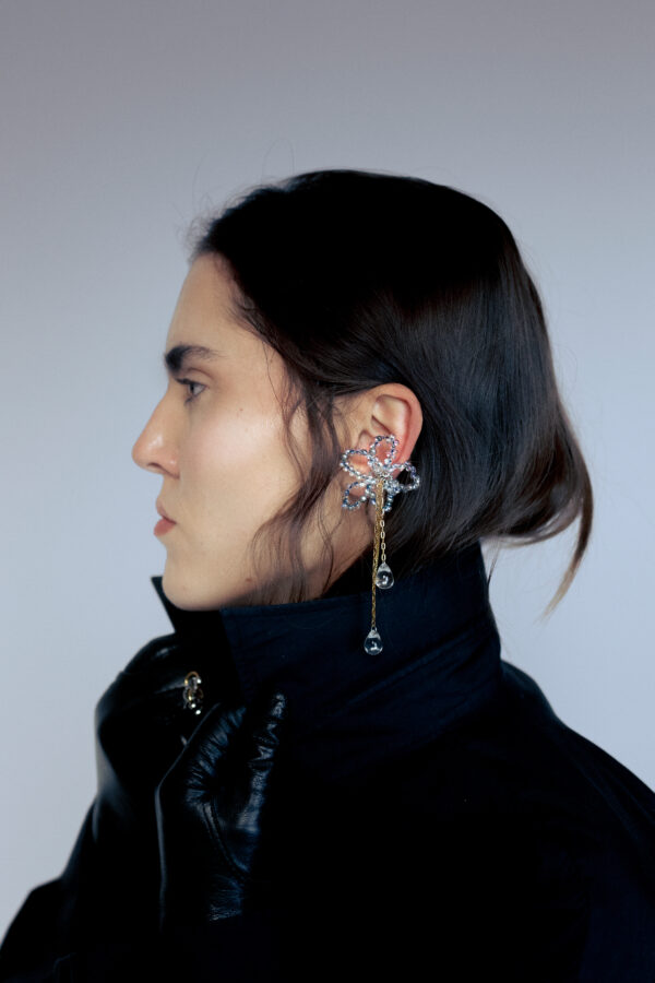 Earcuff en acier inoxydable. Il s’agit d’un faux piercing pour oreille non perçée qui se positionne au niveau du conch ou du lobe suivant la largeur de l’oreille. Il est composé d’un anneau argenté, d'une sculpture en perles en verre en forme de fleur et de chaine doré avec des perles goutte au bout